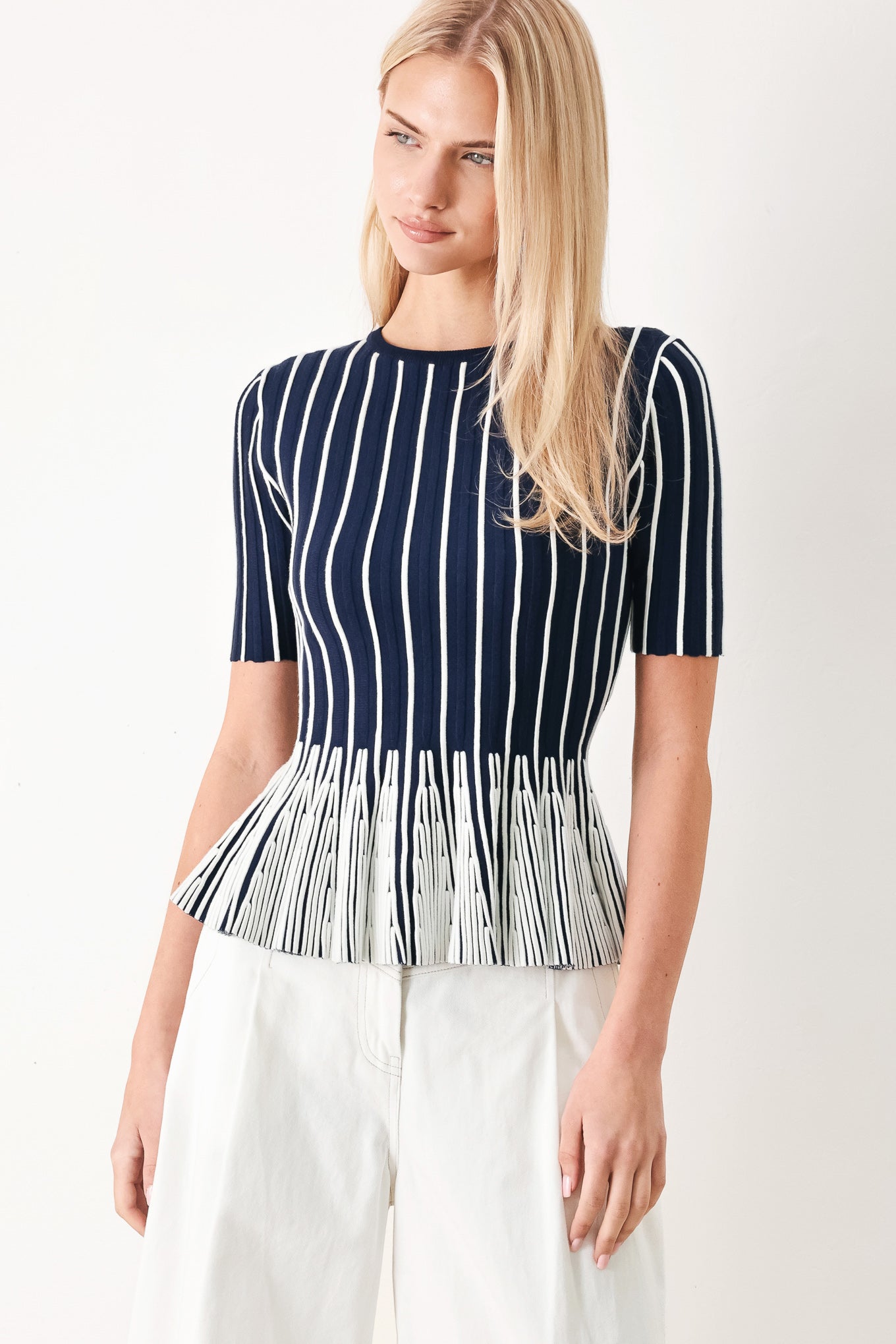 Woman wearing a navy and white striped sweater knit top with a peplum waist | FREEMARKET