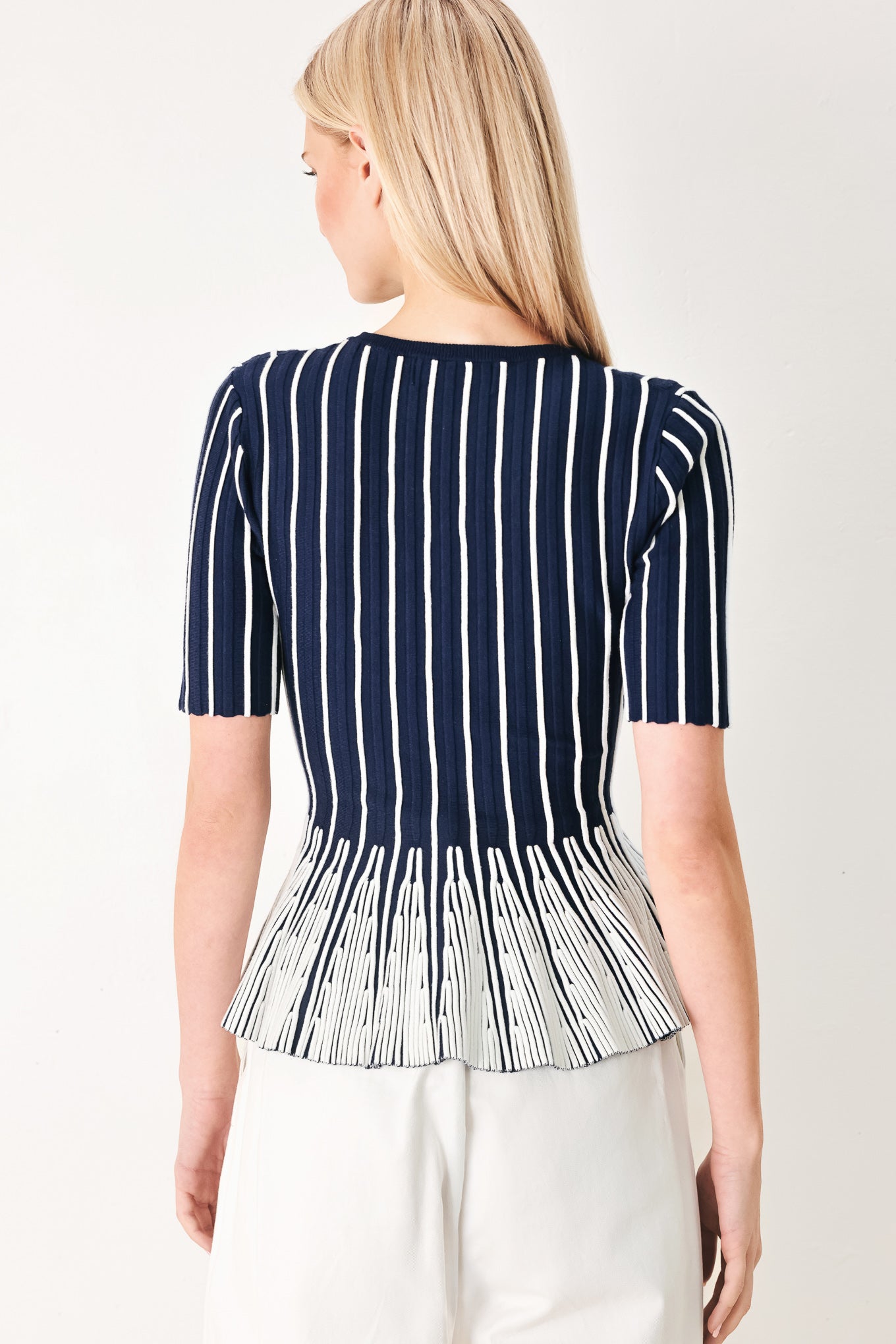 Woman wearing a navy and white striped sweater knit top with a peplum waist | FREEMARKET