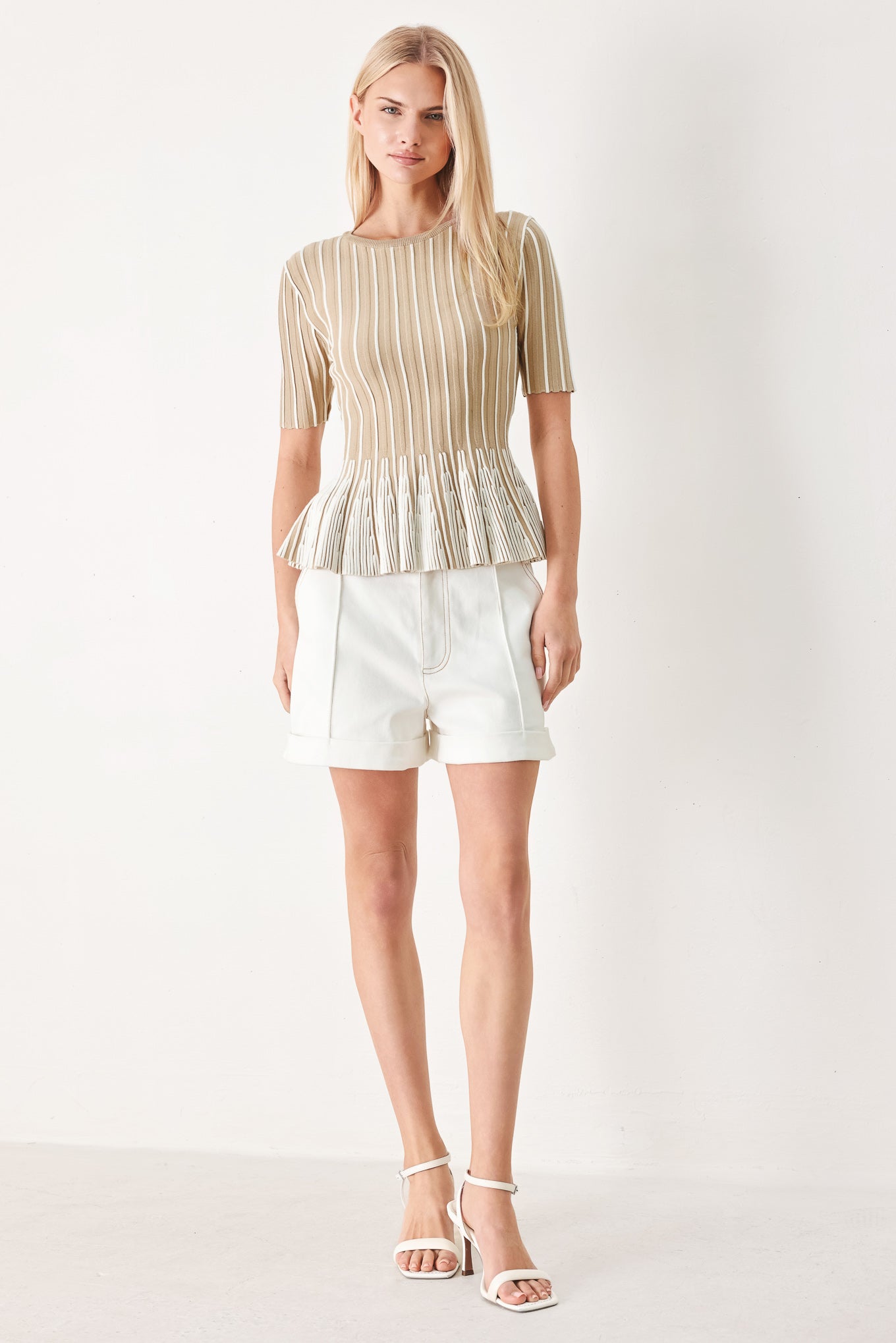 Woman wearing a taupe and white striped sweater knit top with a peplum waist | FREEMARKET