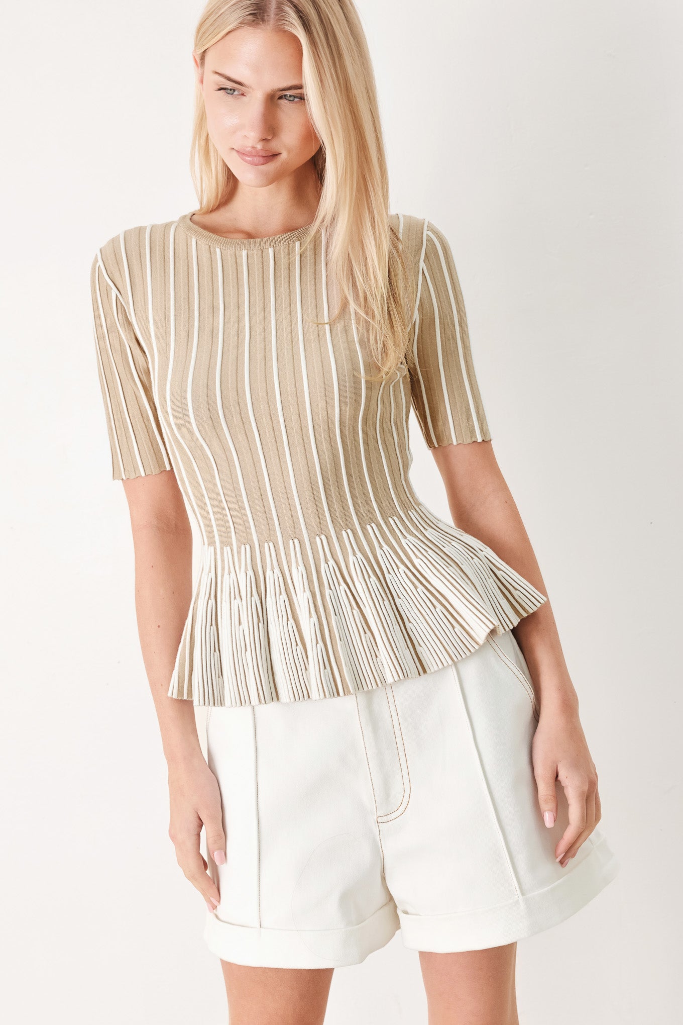 Woman wearing a taupe and white striped sweater knit top with a peplum waist | FREEMARKET