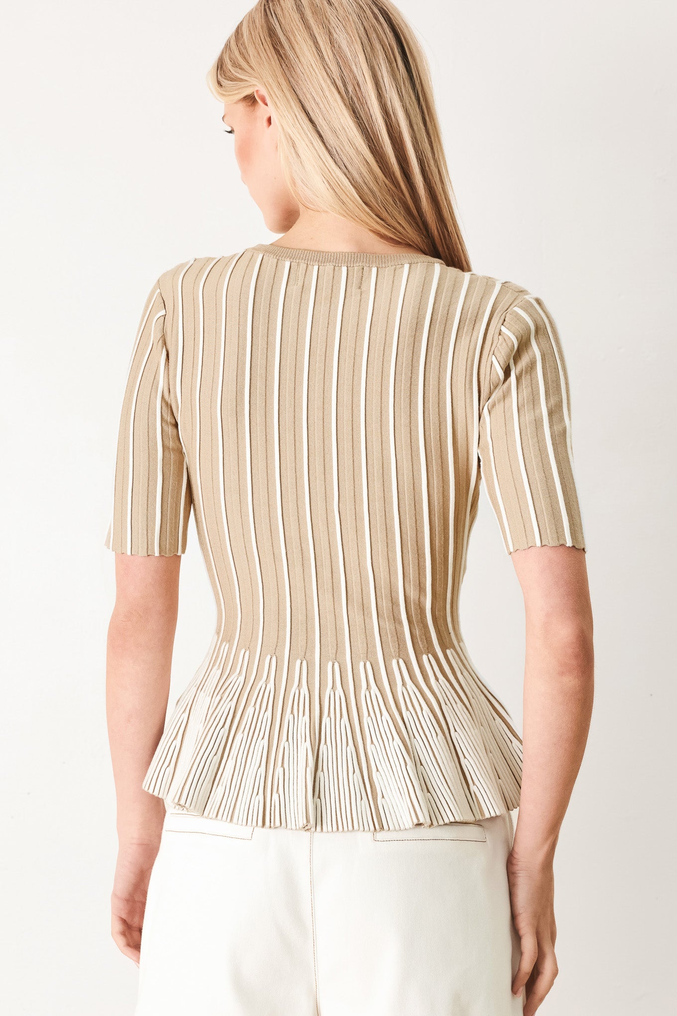 Woman wearing a taupe and white striped sweater knit top with a peplum waist | FREEMARKET