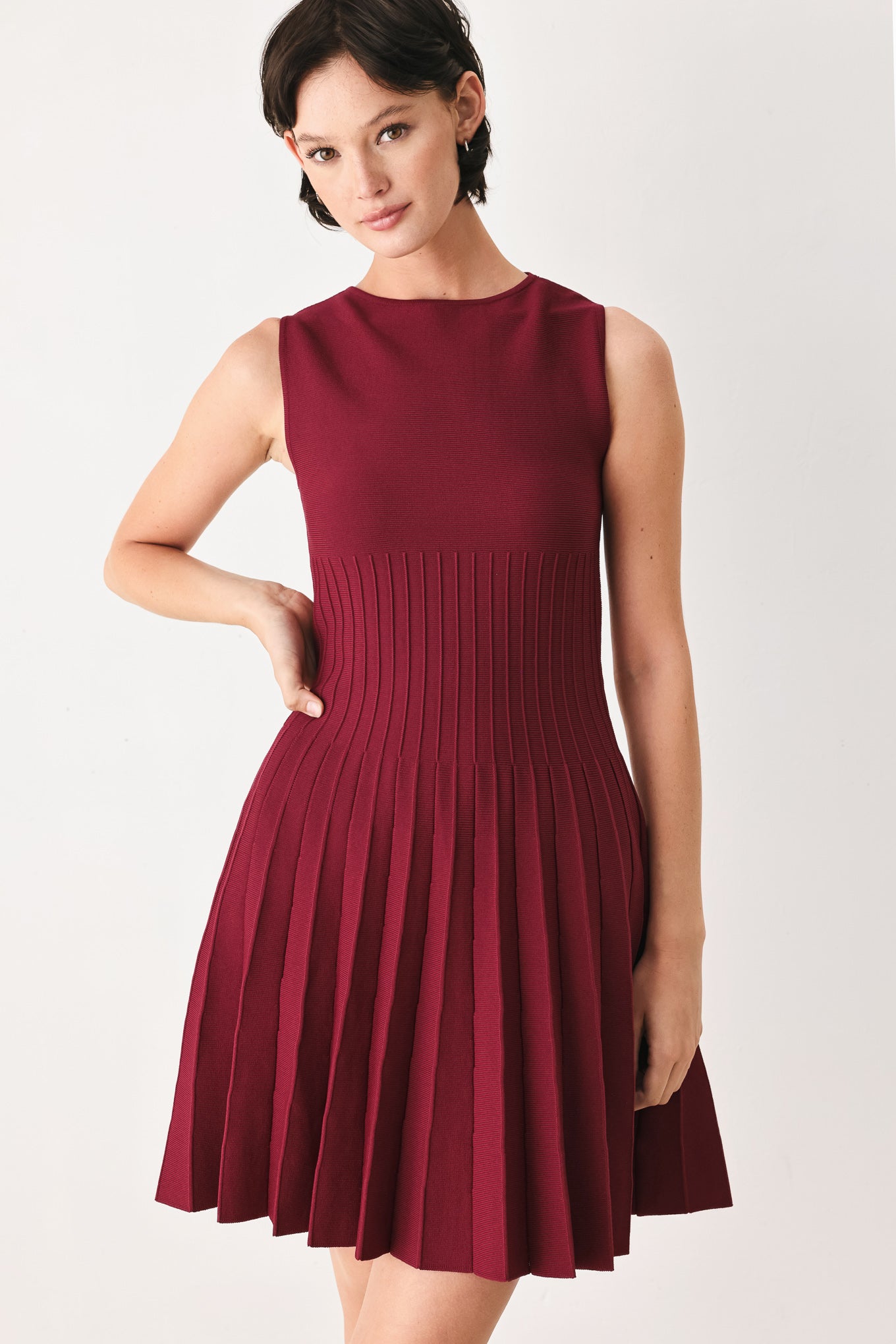 Woman wearing a burgundy sleeveless sweater knit mini dress with wide neckline, and pleated skirt | FREEMARKET
