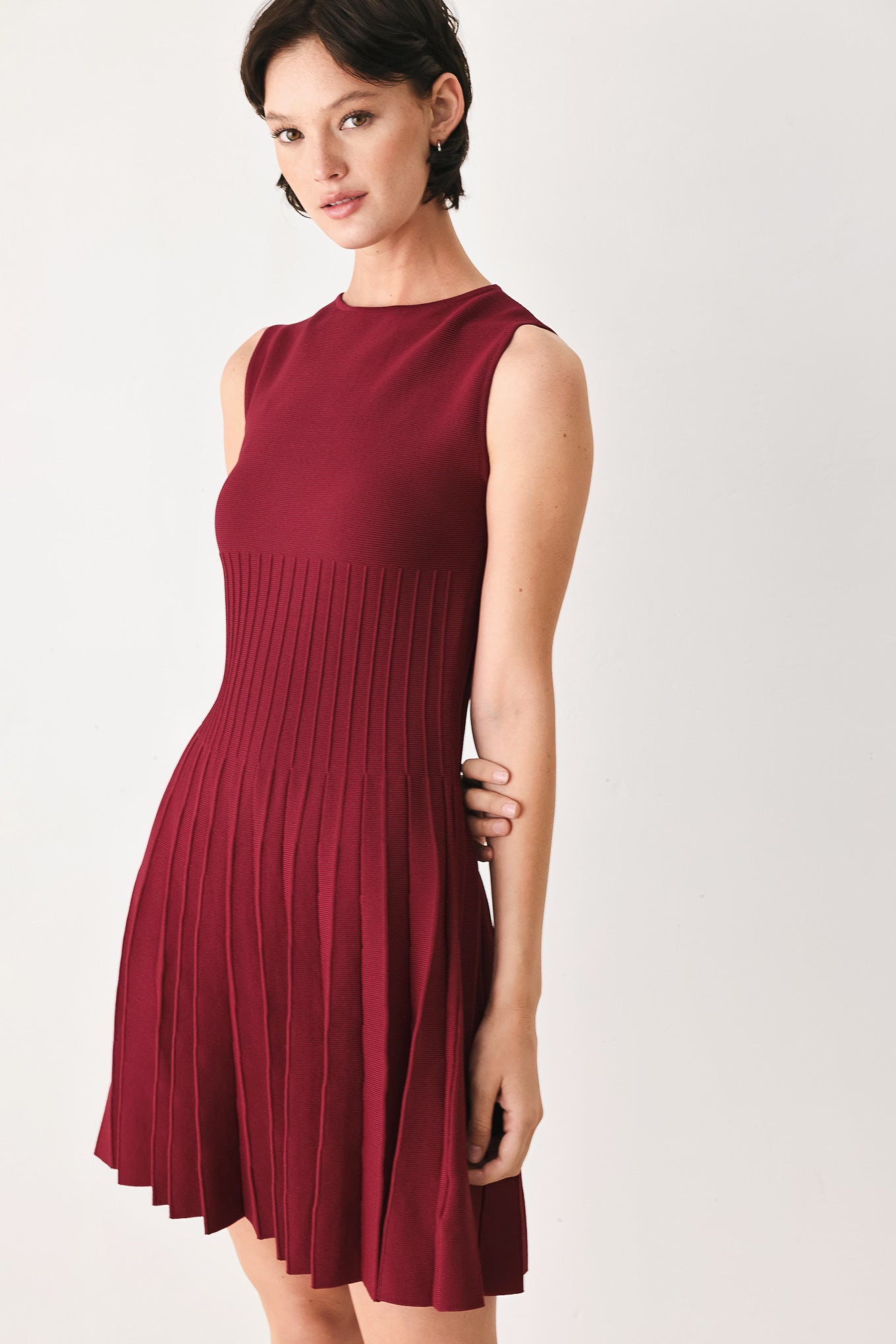 Woman wearing a burgundy sleeveless sweater knit mini dress with wide neckline, and pleated skirt | FREEMARKET