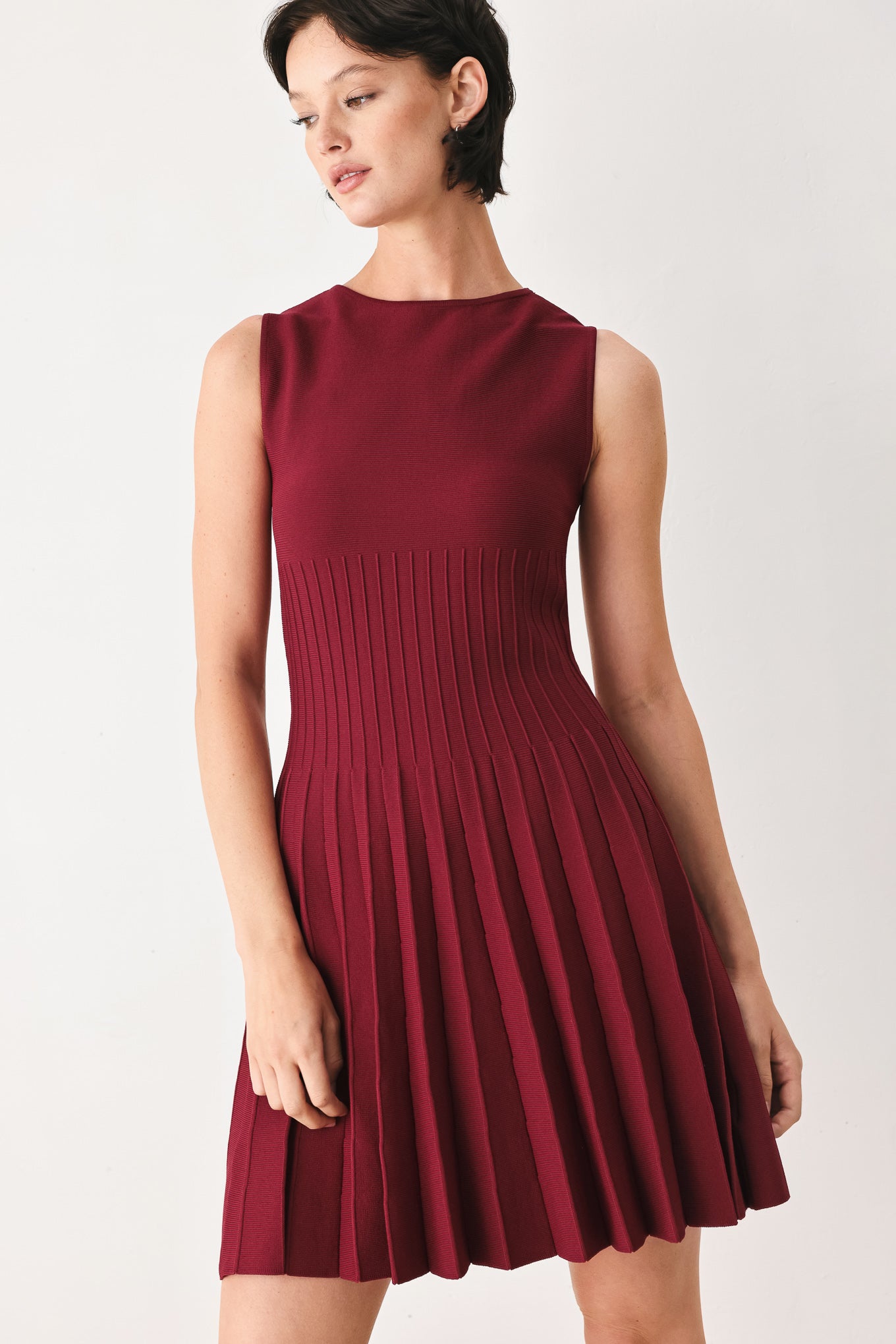 Woman wearing a burgundy sleeveless sweater knit mini dress with wide neckline, and pleated skirt | FREEMARKET