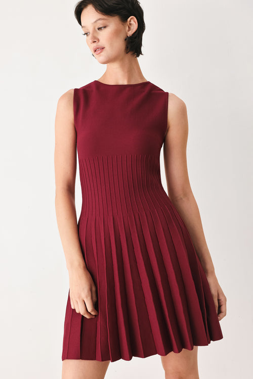 Woman wearing a burgundy sleeveless sweater knit mini dress with wide neckline, and pleated skirt | FREEMARKET