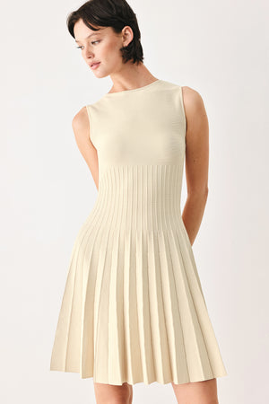 Woman wearing a ivory cream sleeveless sweater knit mini dress with wide neckline, and pleated skirt | FREEMARKET