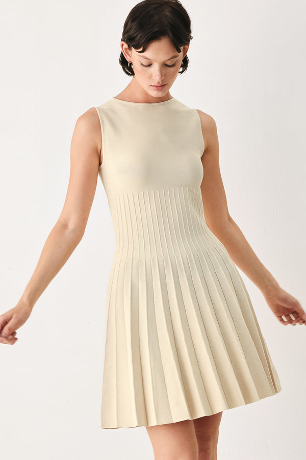 Woman wearing a ivory cream sleeveless sweater knit mini dress with wide neckline, and pleated skirt | FREEMARKET