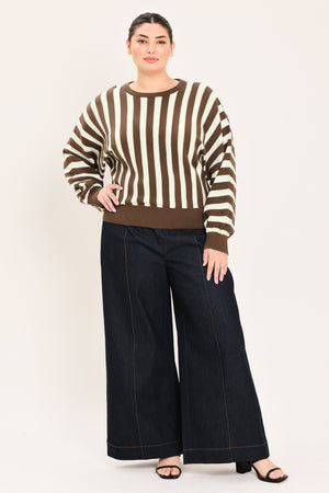 A woman wearing a brown and cream vertical striped knit sweater with long balloon sleeves and ribbed cuffs, paired with dark jeans | Plus Curve Flying Tomato