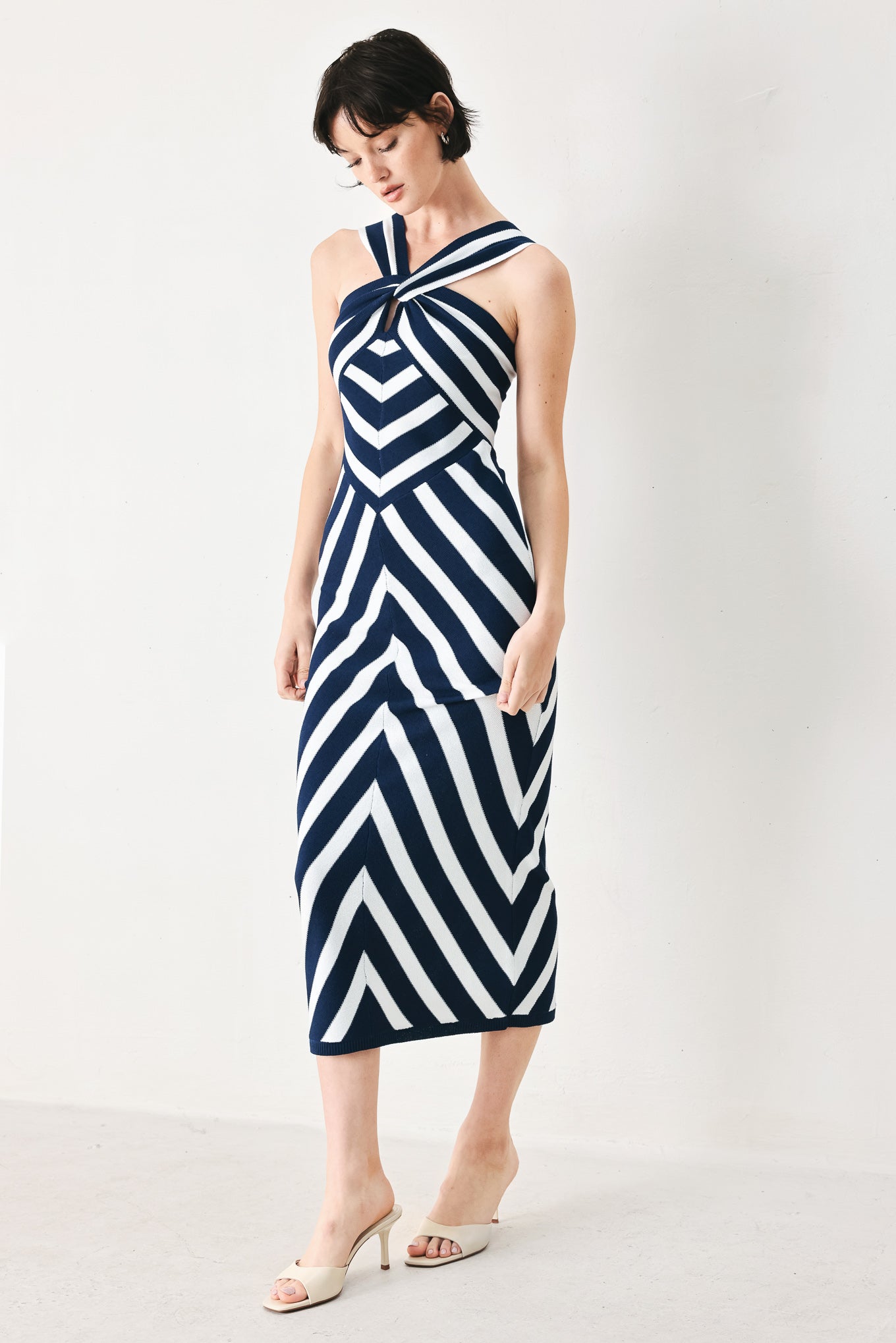 Woman wearing a navy and white striped sweater knit midi dress with front twist halter neckline | FREEMARKET