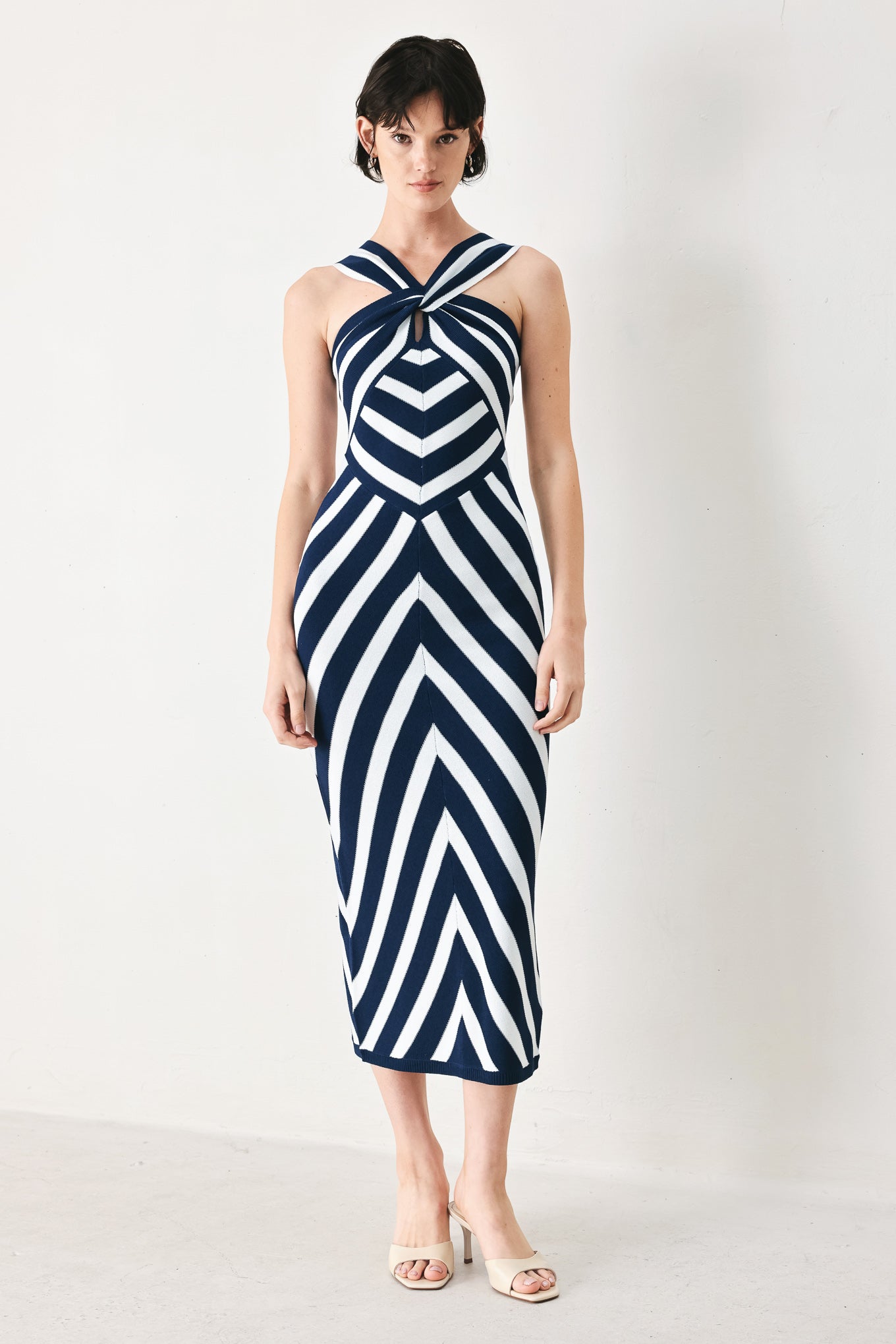 Woman wearing a navy and white striped sweater knit midi dress with front twist halter neckline | FREEMARKET