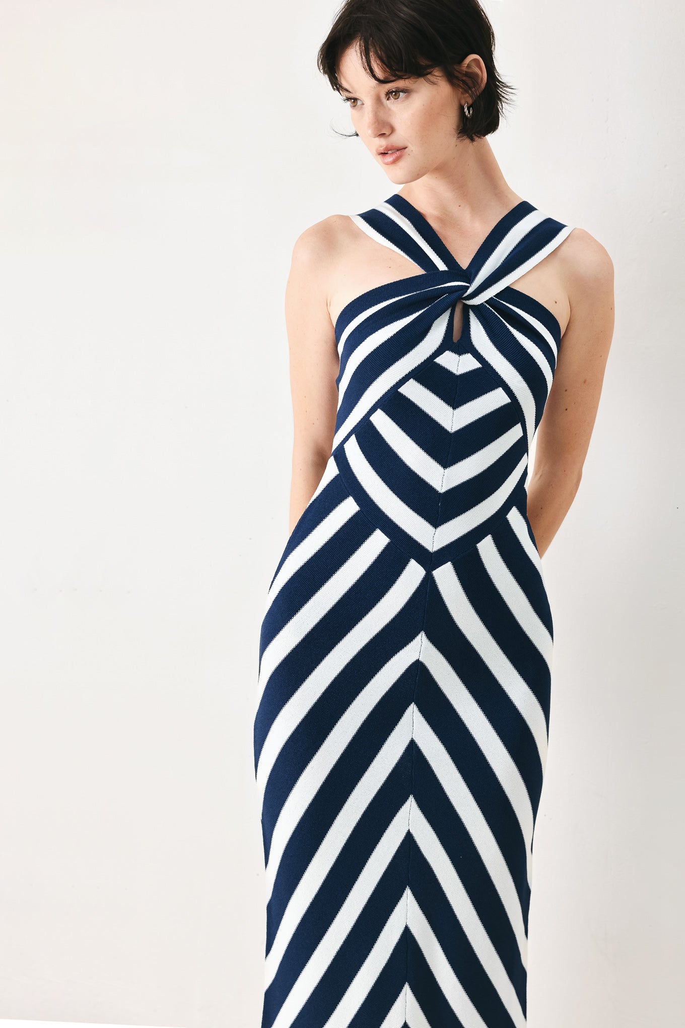 Woman wearing a navy and white striped sweater knit midi dress with front twist halter neckline | FREEMARKET