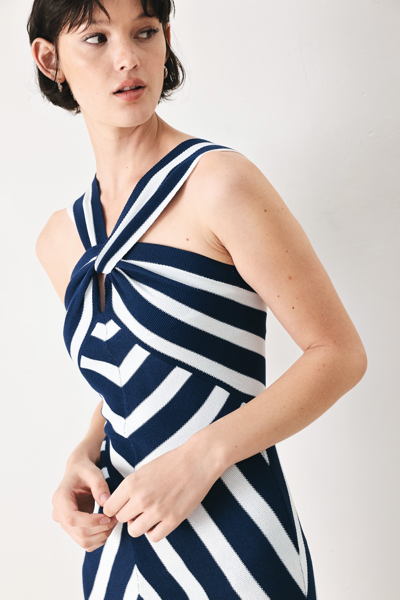 Woman wearing a navy and white striped sweater knit midi dress with front twist halter neckline | FREEMARKET