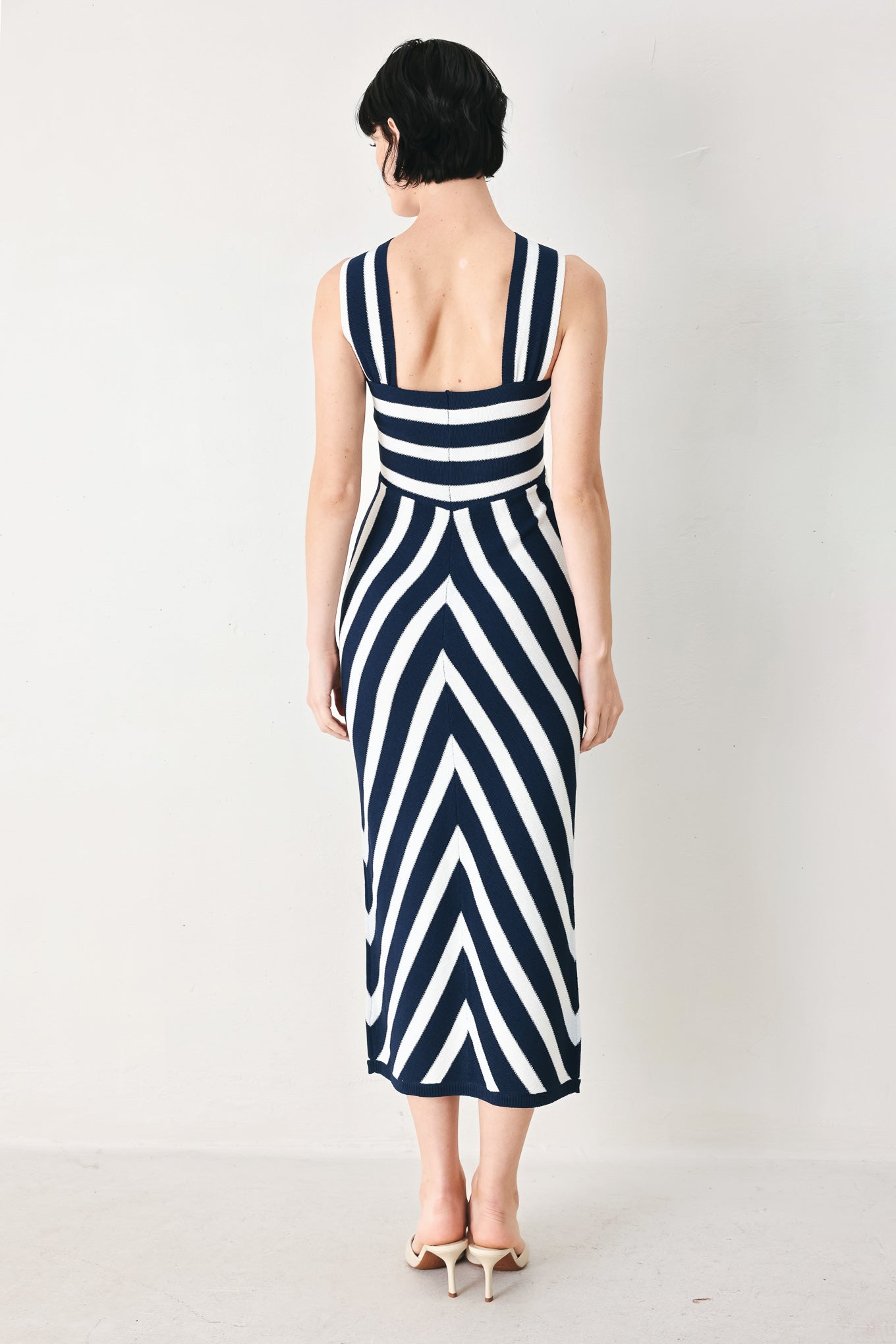 Woman wearing a navy and white striped sweater knit midi dress with front twist halter neckline | FREEMARKET
