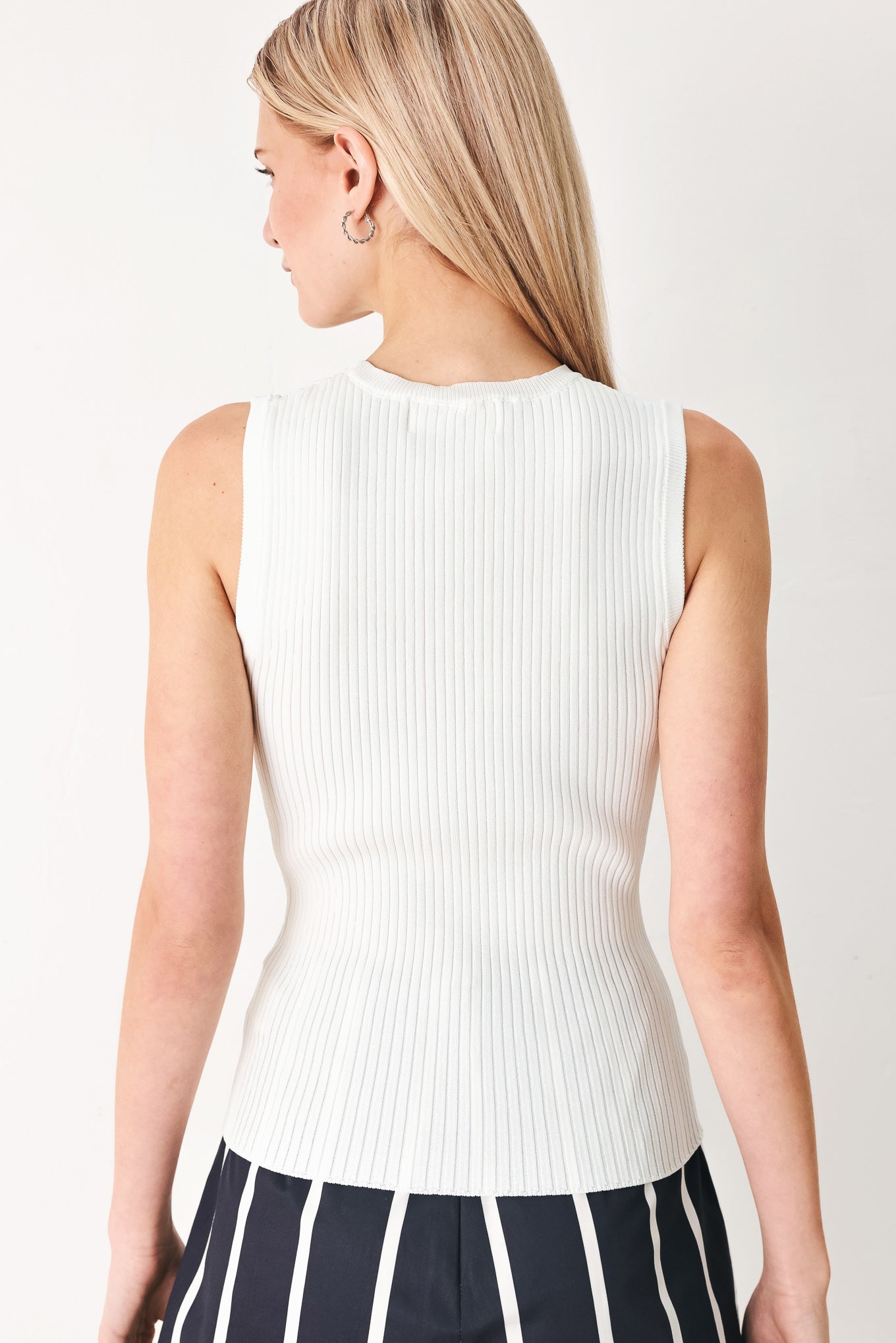 Woman wearing a white ribbed sleeveless top with a cutout design | FREEMARKET