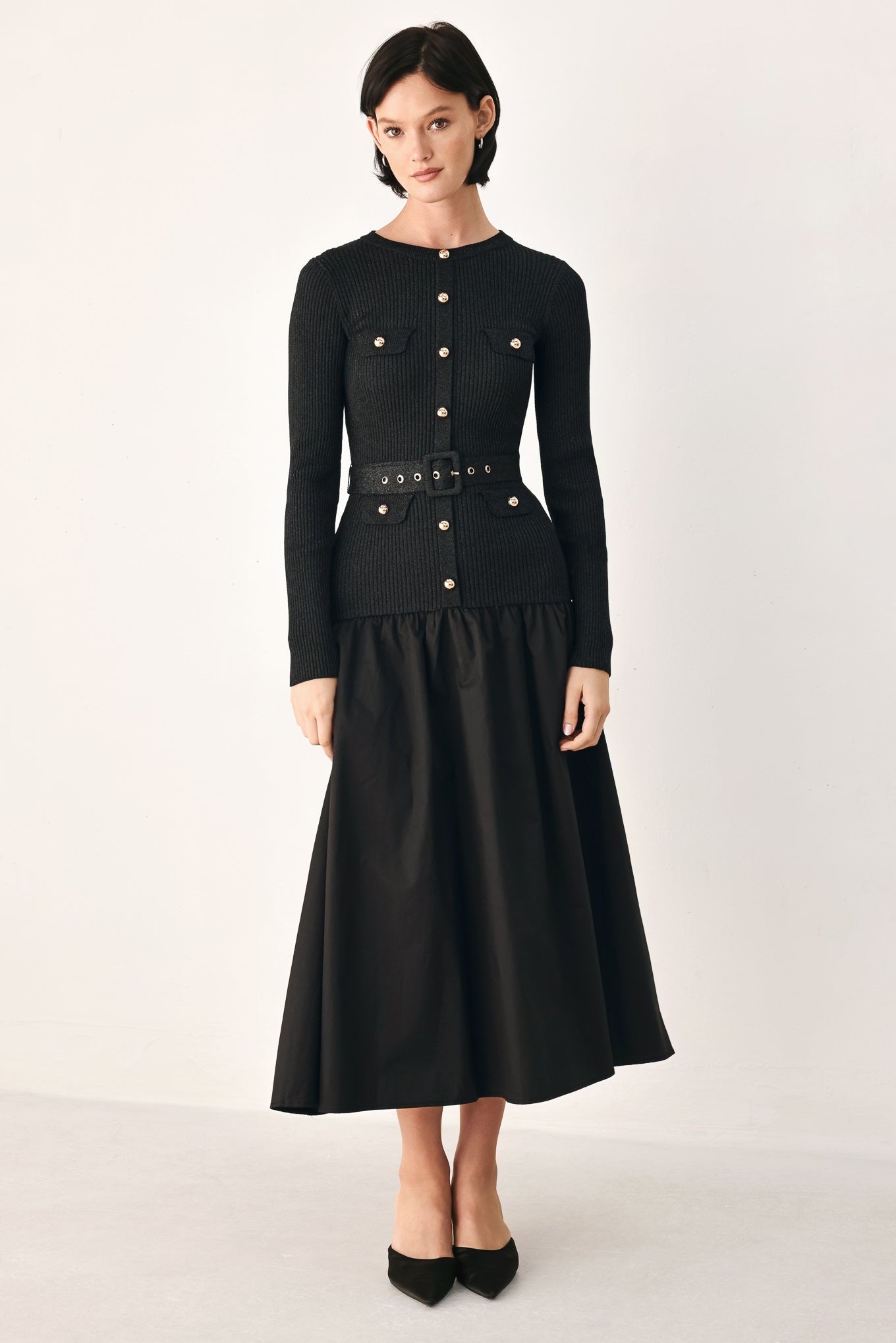 A model wearing a black long-sleeve midi dress with gold-tone decorative buttons down the front, a matching black belt with gold studs, and a flared drop-waist skirt | FREEMARKET