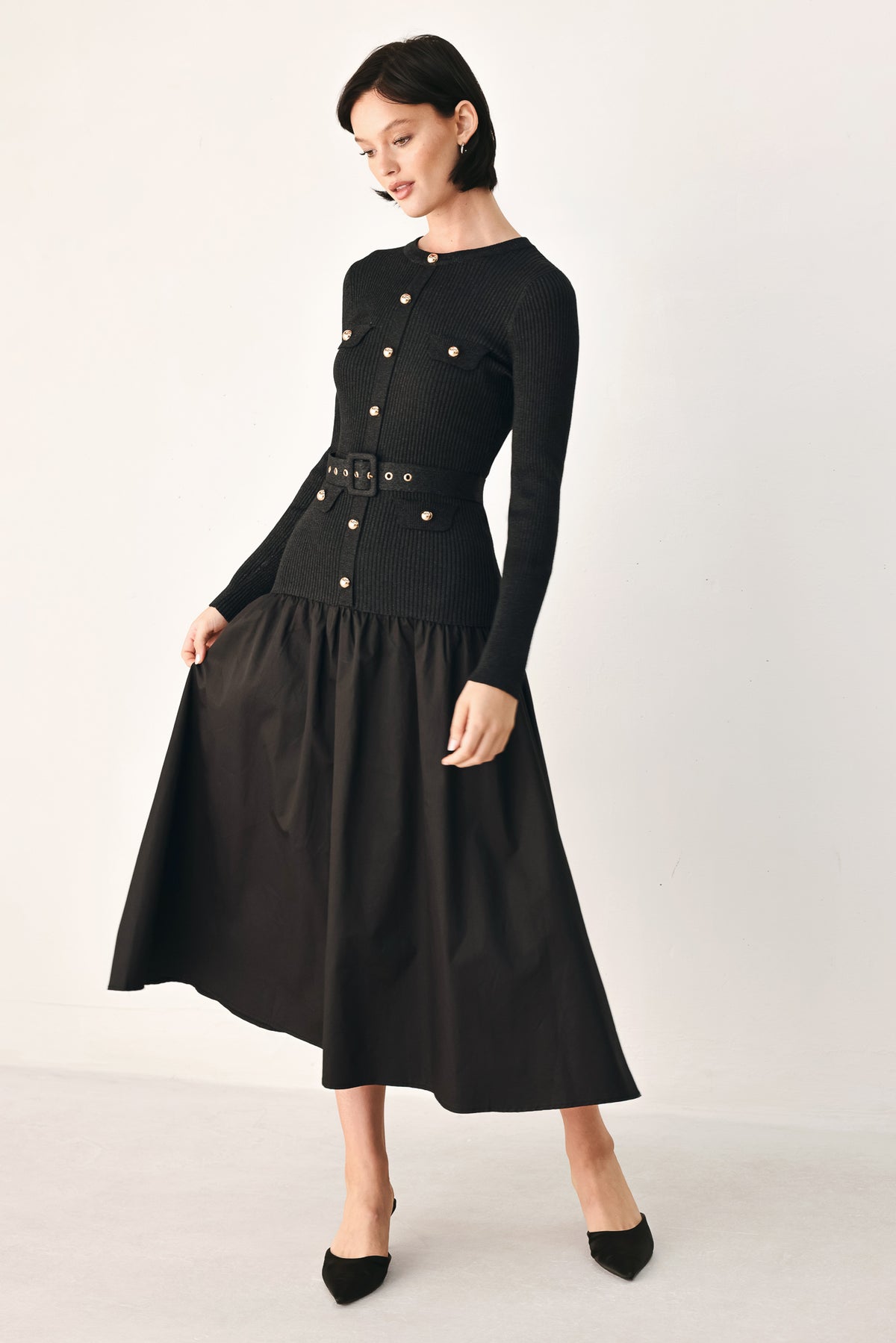 A model wearing a black long-sleeve midi dress with gold-tone decorative buttons down the front, a matching black belt with gold studs, and a flared drop-waist skirt | FREEMARKET