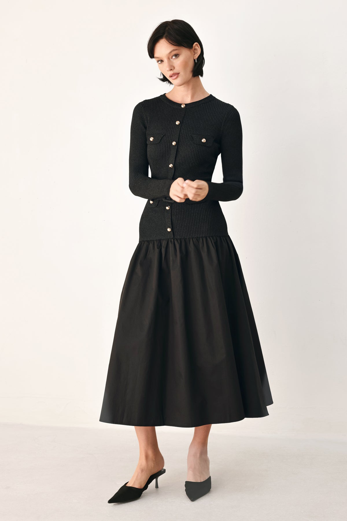 A model wearing a black long-sleeve midi dress with gold-tone decorative buttons down the front, a matching black belt with gold studs, and a flared drop-waist skirt | FREEMARKET
