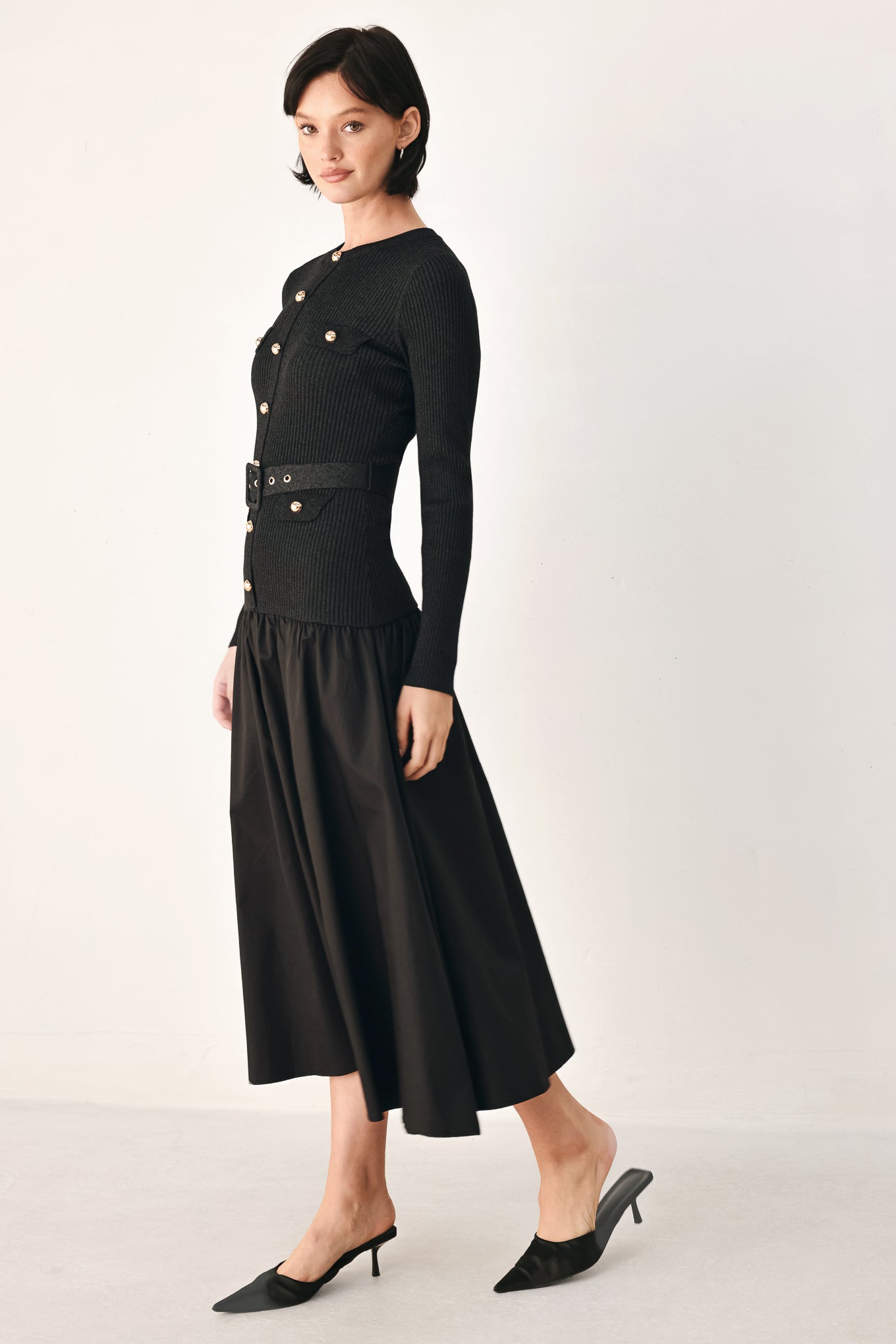 A model wearing a black long-sleeve midi dress with gold-tone decorative buttons down the front, a matching black belt with gold studs, and a flared drop-waist skirt | FREEMARKET