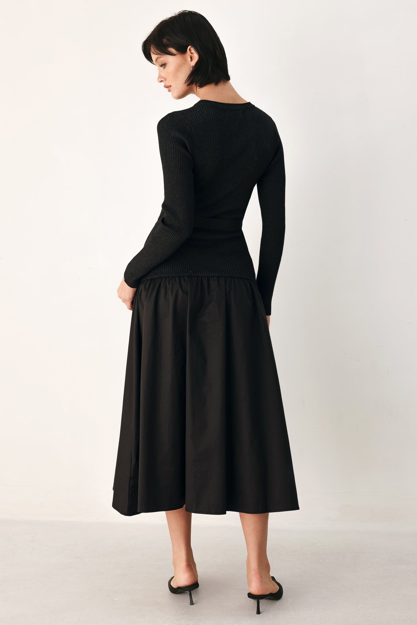 A model wearing a black long-sleeve midi dress with gold-tone decorative buttons down the front, a matching black belt with gold studs, and a flared drop-waist skirt | FREEMARKET