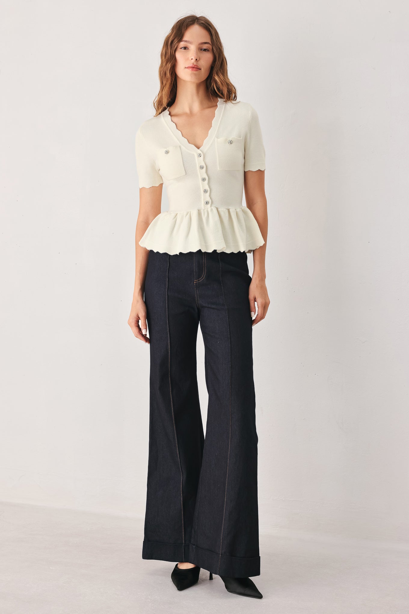 A woman wearing a short-sleeve off-white sweater knit blouse with a scalloped V-neckline, front buttons, and chest pockets | FREEMARKET
