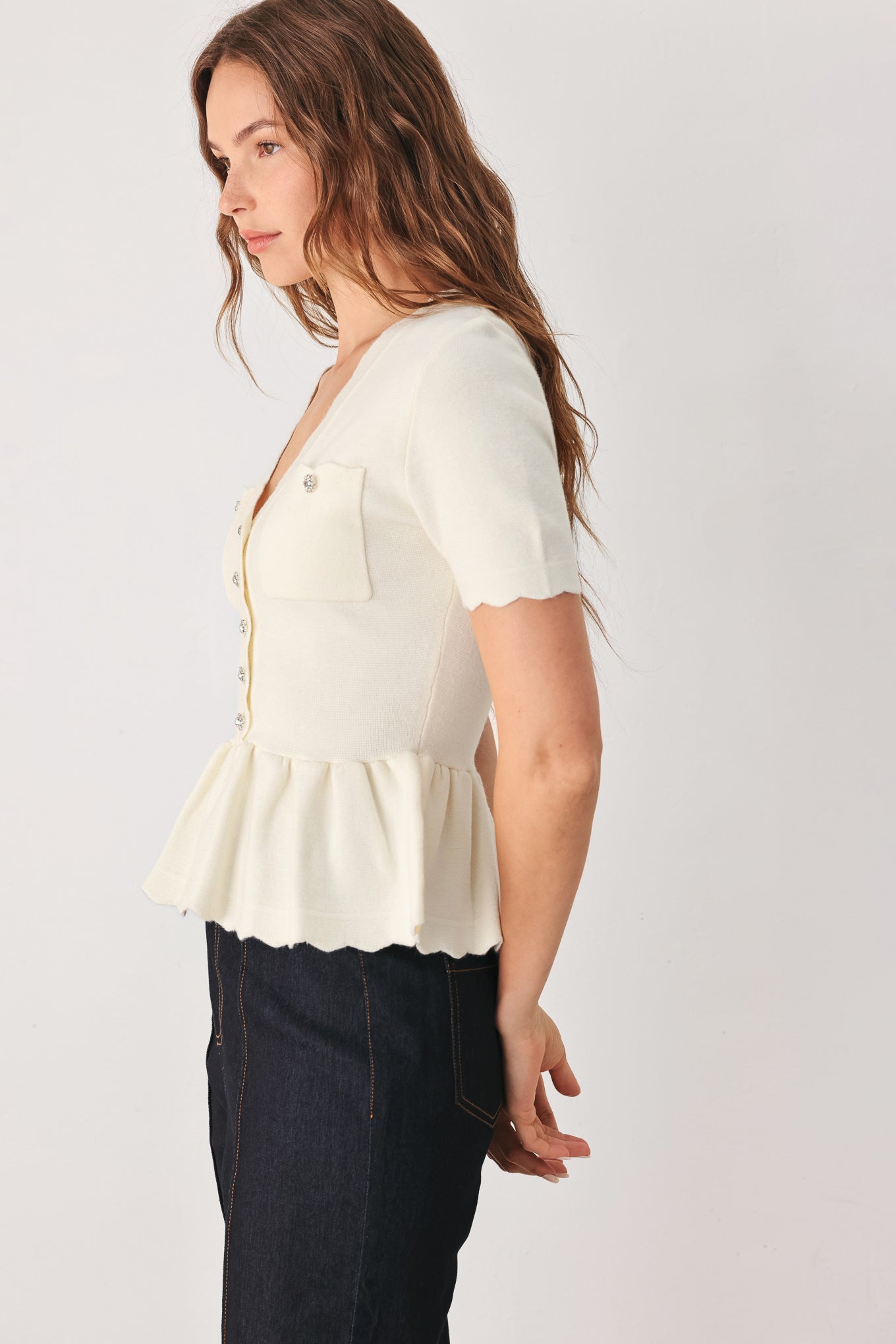 A woman wearing a short-sleeve off-white sweater knit blouse with a scalloped V-neckline, front buttons, and chest pockets | FREEMARKET
