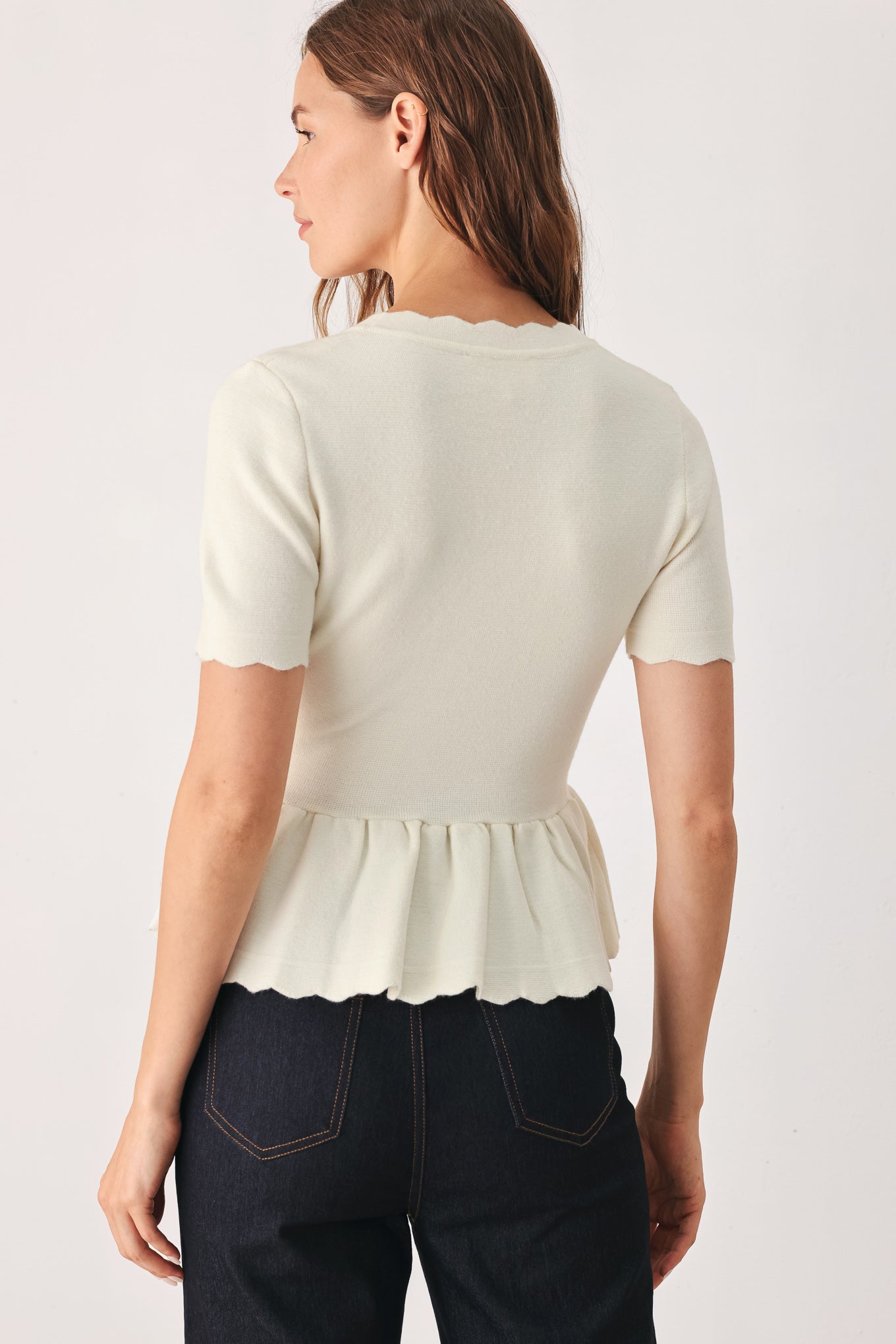 A woman wearing a short-sleeve off-white sweater knit blouse with a scalloped V-neckline, front buttons, and chest pockets | FREEMARKET