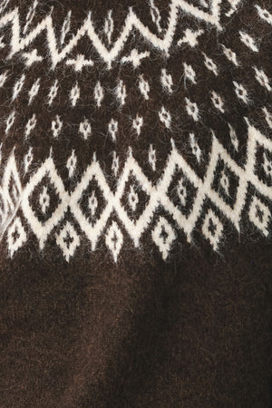 A model stands against a light gray studio background wearing a dark brown knit sweater with a white geometric pattern across the chest | FREEMARKET