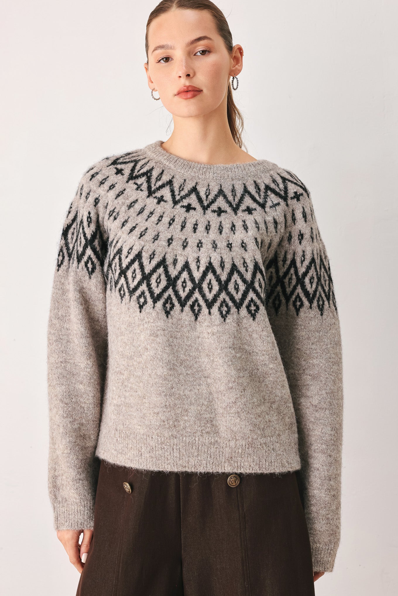 A model wearing a taupe knit sweater with a black geometric pattern across the chest | FREEMARKET