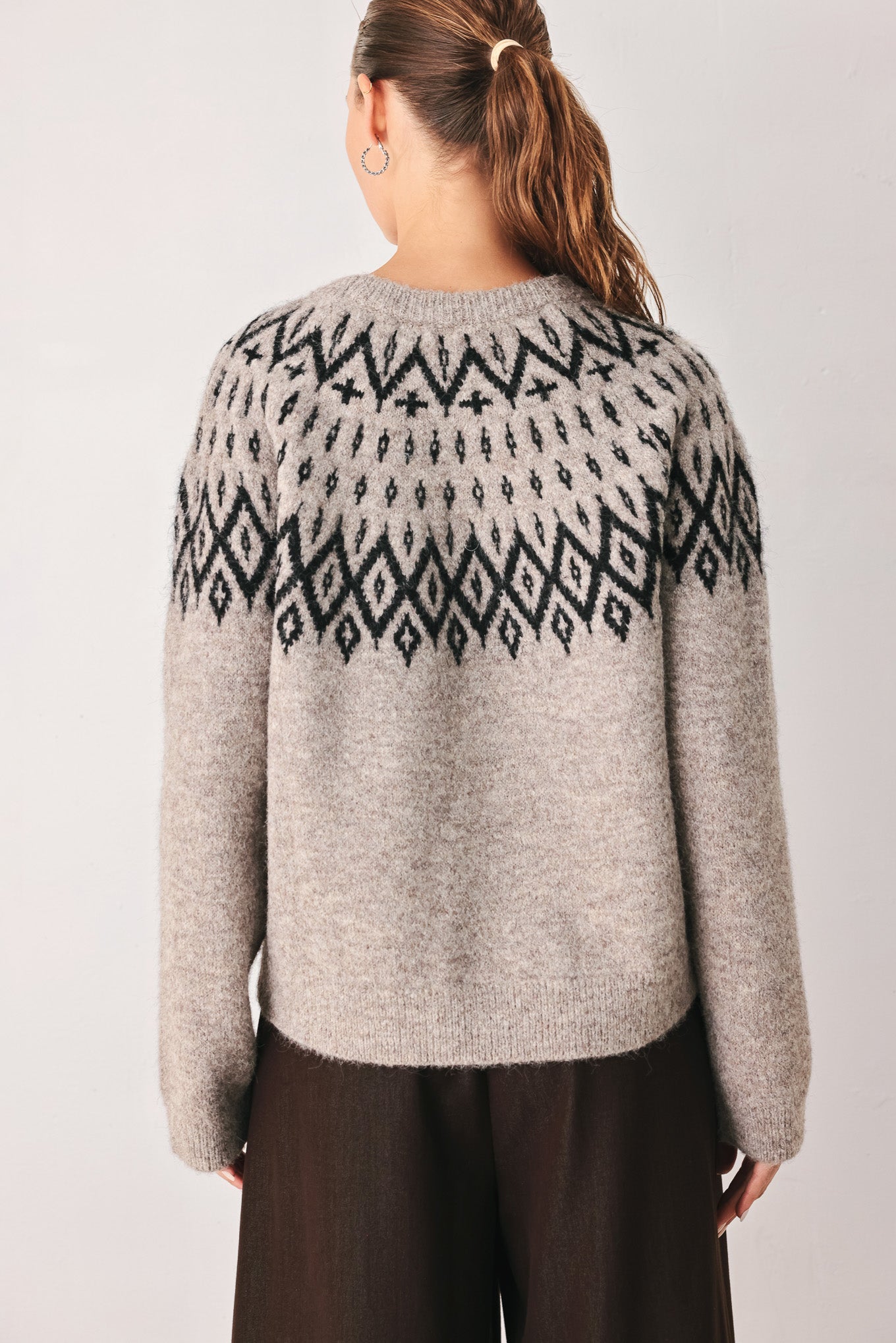 A model wearing a taupe knit sweater with a black geometric pattern across the chest | FREEMARKET