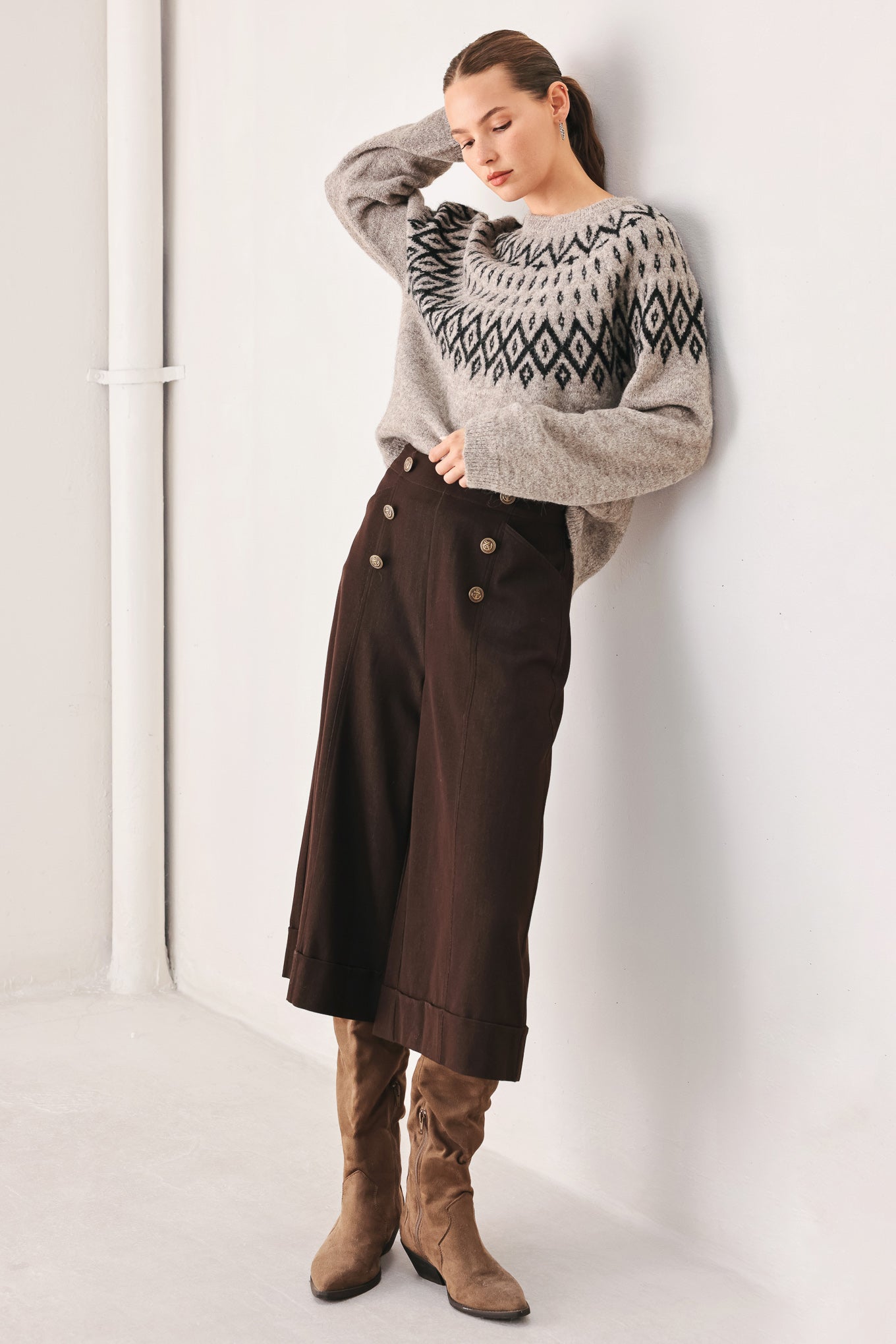 A model wearing a taupe knit sweater with a black geometric pattern across the chest | FREEMARKET
