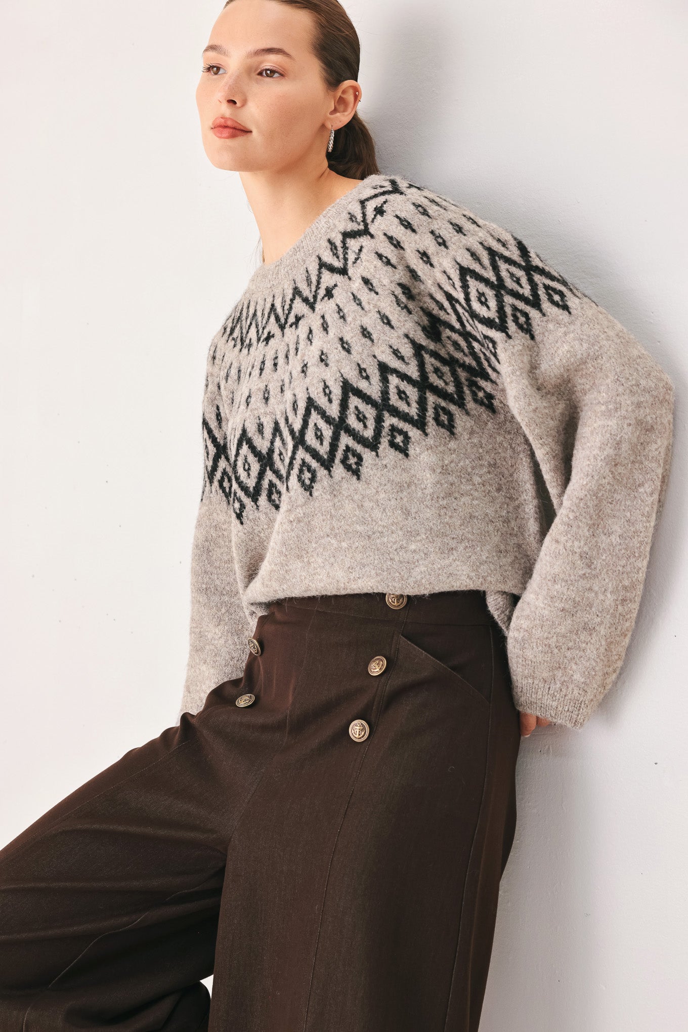 A model wearing a taupe knit sweater with a black geometric pattern across the chest | FREEMARKET