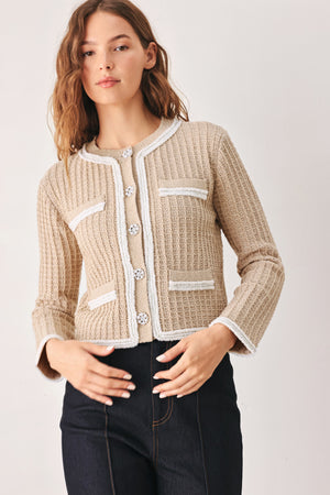 A woman wearing a beige textured knit cardigan with white trim and decorative buttons | FREEMARKET