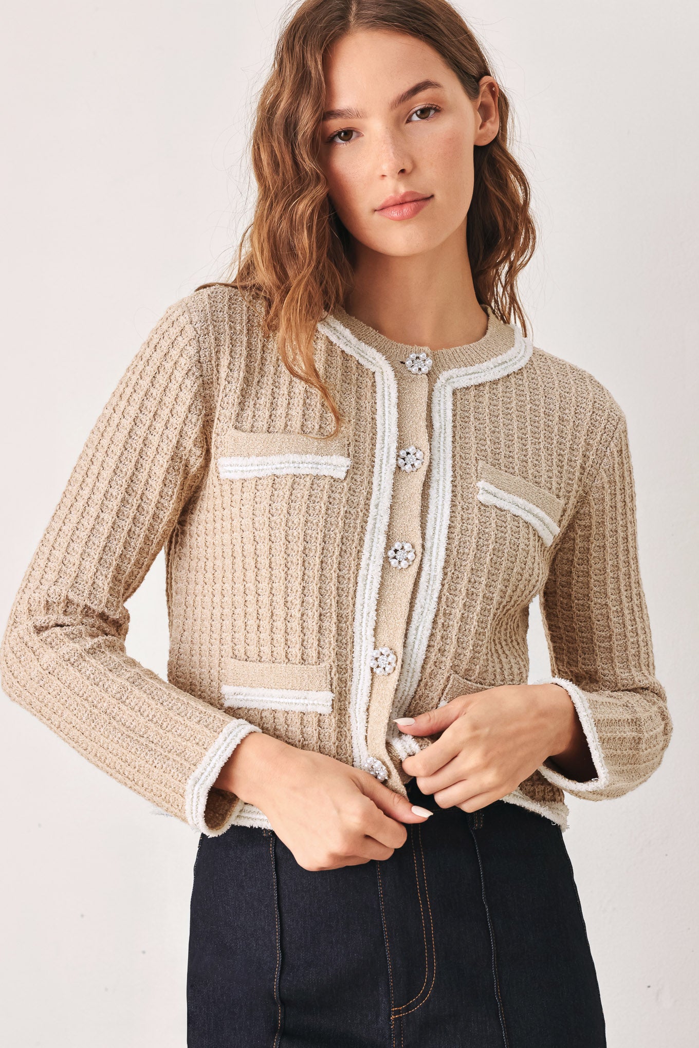 A woman wearing a beige textured knit cardigan with white trim and decorative buttons | FREEMARKET