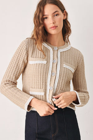 A woman wearing a beige textured knit cardigan with white trim and decorative buttons | FREEMARKET