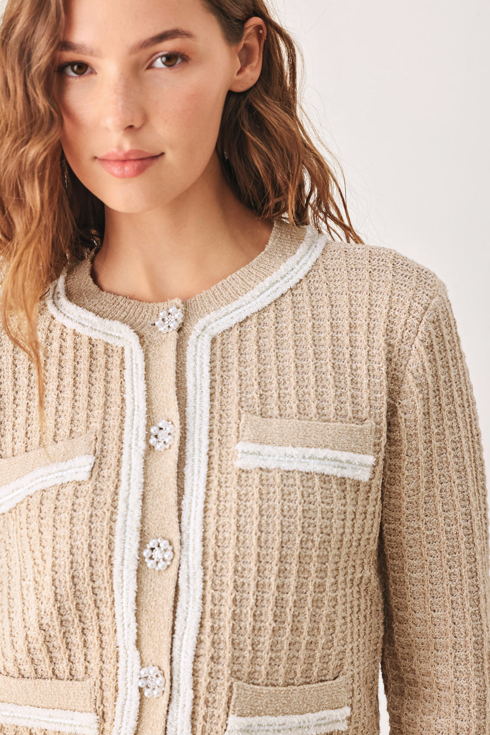 A woman wearing a beige textured knit cardigan with white trim and decorative buttons | FREEMARKET