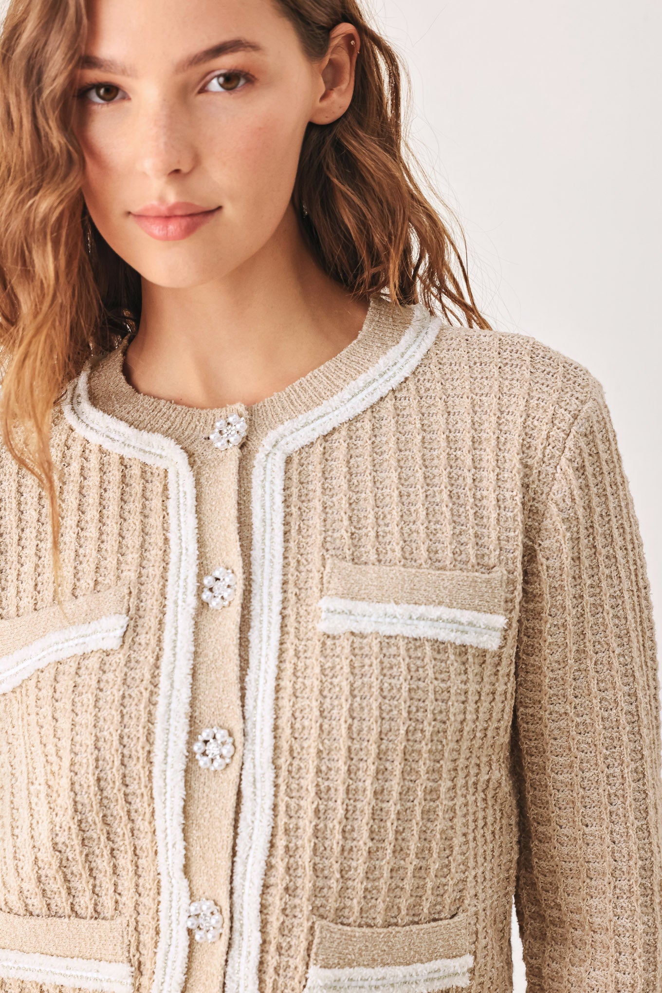 A woman wearing a beige textured knit cardigan with white trim and decorative buttons | FREEMARKET