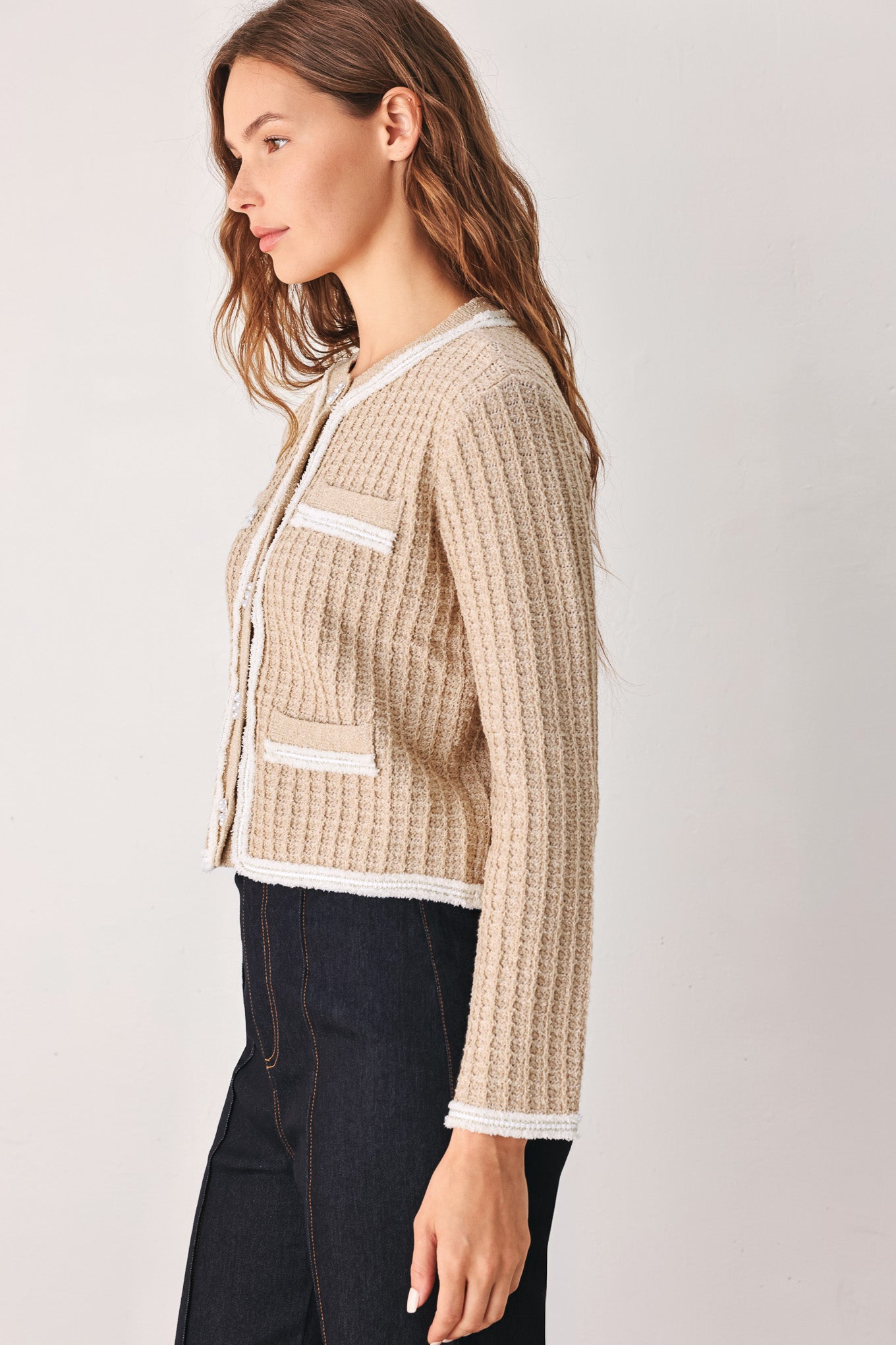 A woman wearing a beige textured knit cardigan with white trim and decorative buttons | FREEMARKET