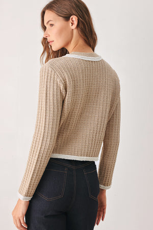 A woman wearing a beige textured knit cardigan with white trim and decorative buttons | FREEMARKET