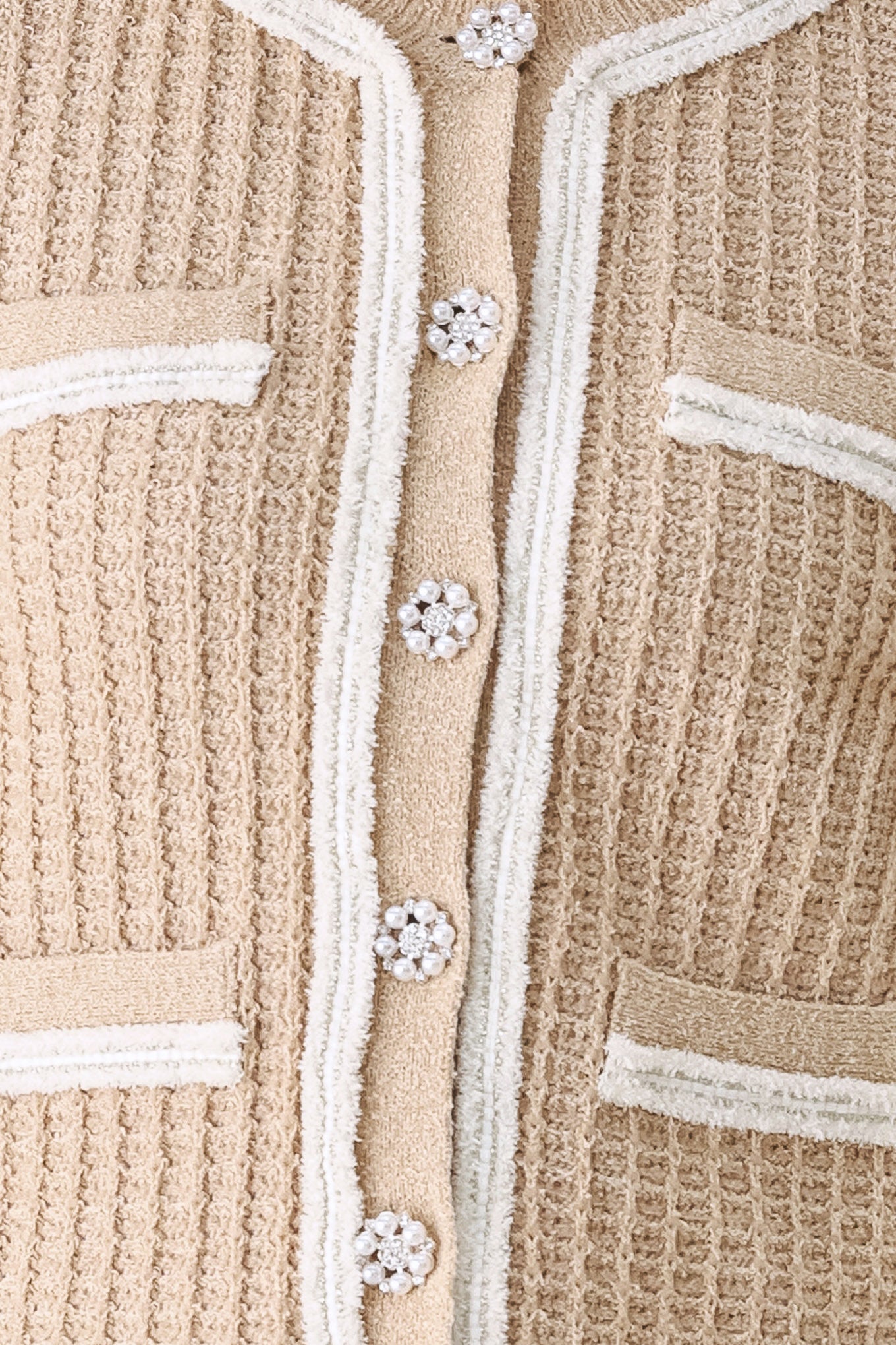 A woman wearing a beige textured knit cardigan with white trim and decorative buttons | FREEMARKET