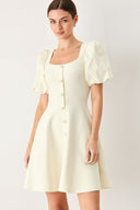 Woman wearing a light ivory sweater knit mini dress with puff sleeves featuring U neckline and front button down | FREEMARKET