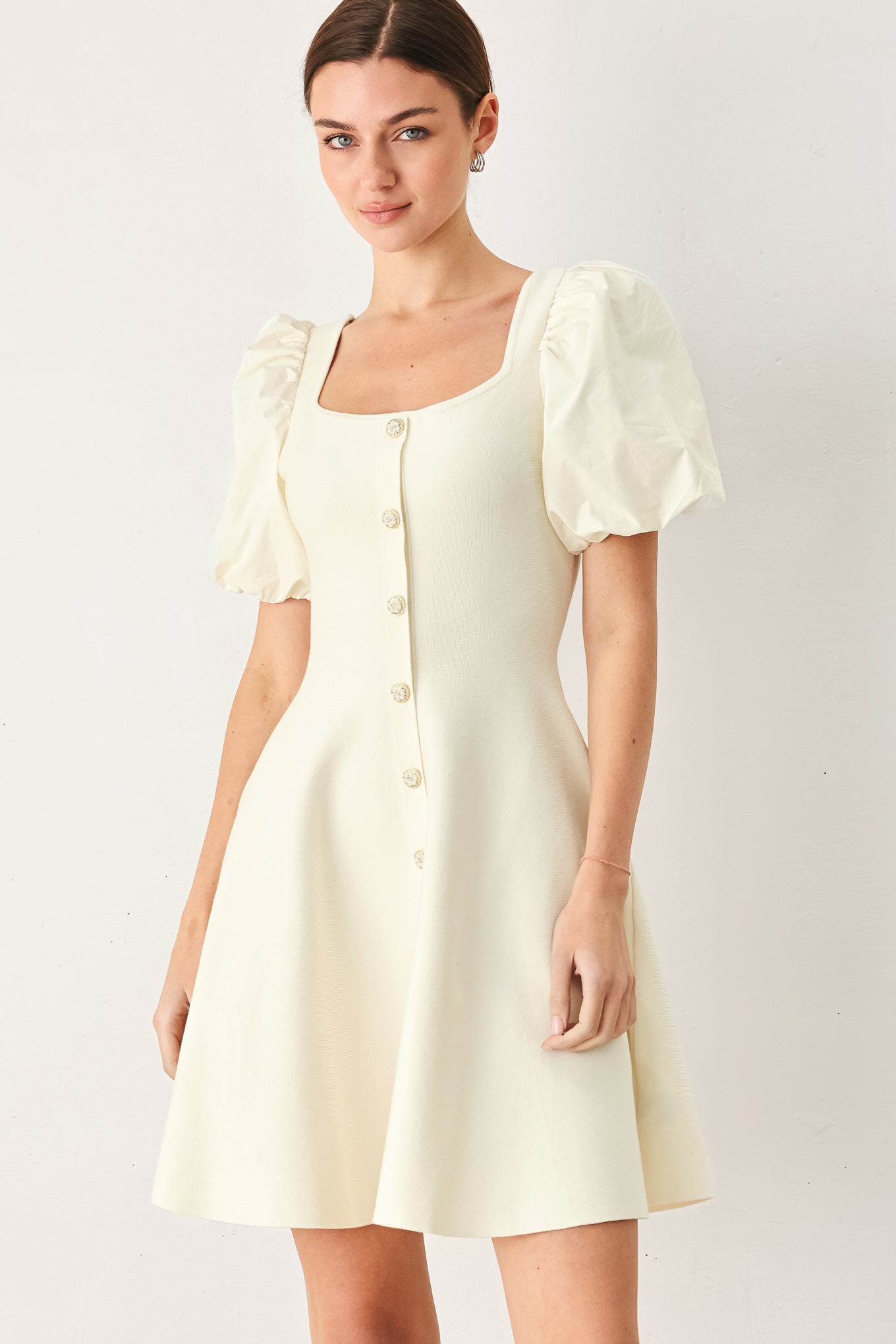 Woman wearing a light yellow dress with puff sleeves against a white background