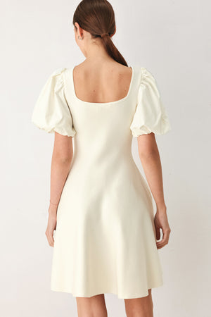 Woman wearing a light ivory sweater knit mini dress with puff sleeves featuring U neckline and front button down | FREEMARKET