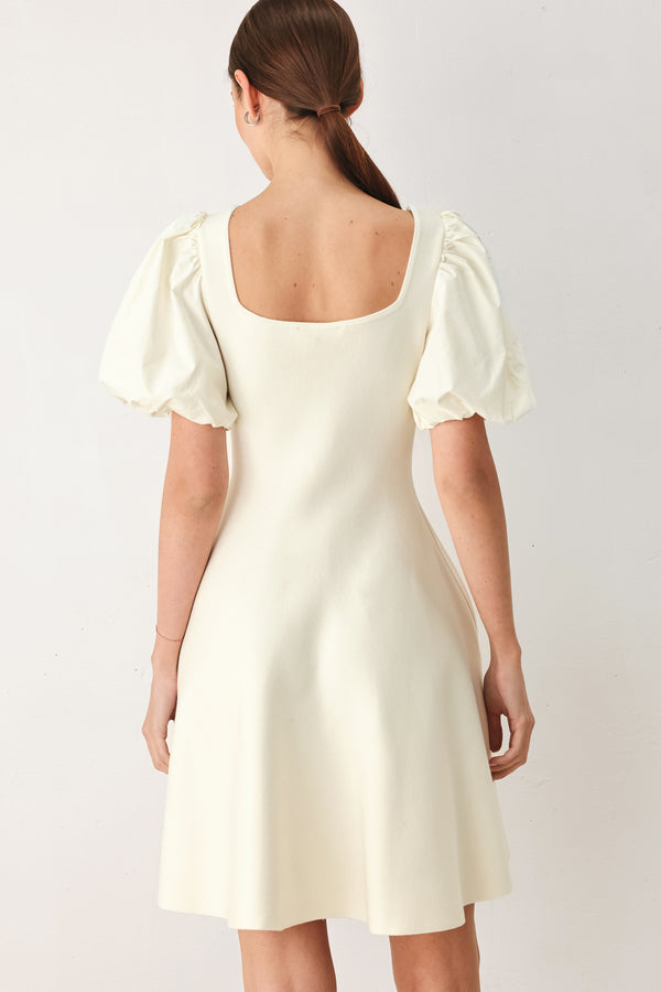 Woman wearing a light ivory sweater knit mini dress with puff sleeves featuring U neckline and front button down | FREEMARKET