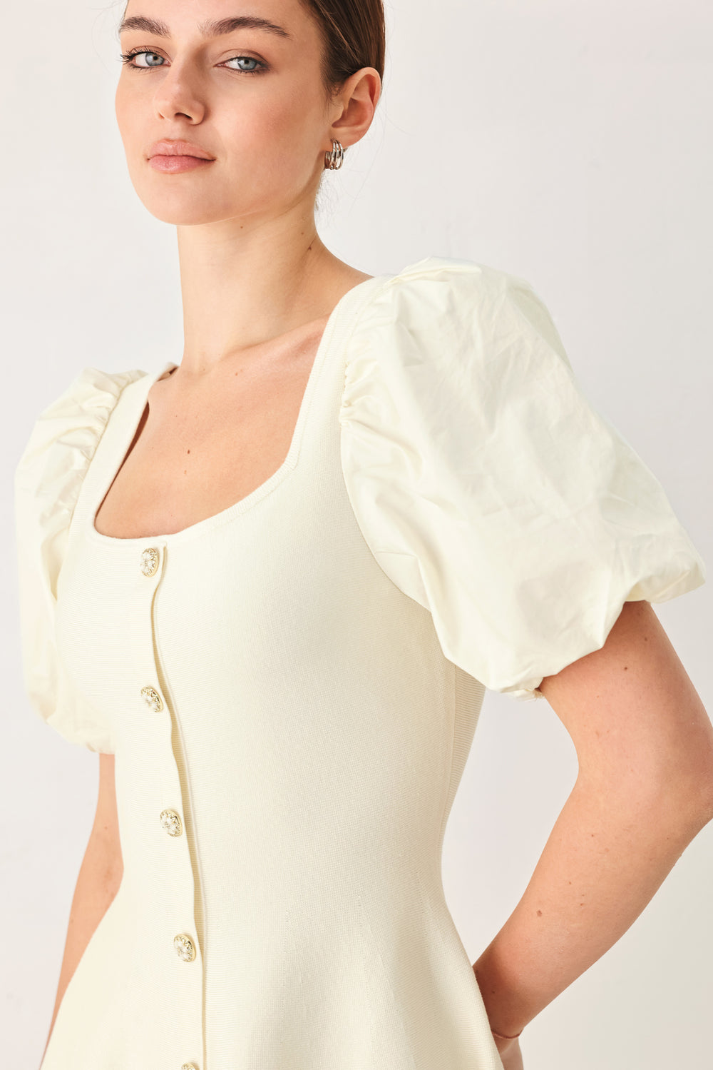 Woman wearing a light ivory sweater knit mini dress with puff sleeves featuring U neckline and front button down | FREEMARKET