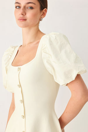 Woman wearing a light ivory sweater knit mini dress with puff sleeves featuring U neckline and front button down | FREEMARKET