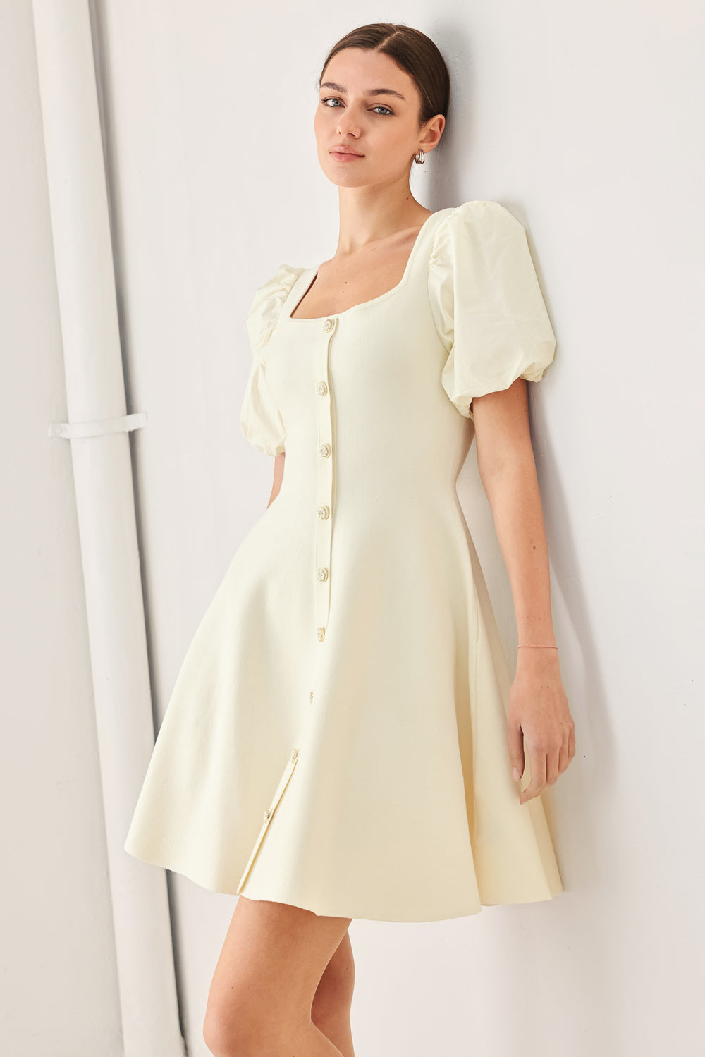 Woman wearing a light ivory sweater knit mini dress with puff sleeves featuring U neckline and front button down | FREEMARKET