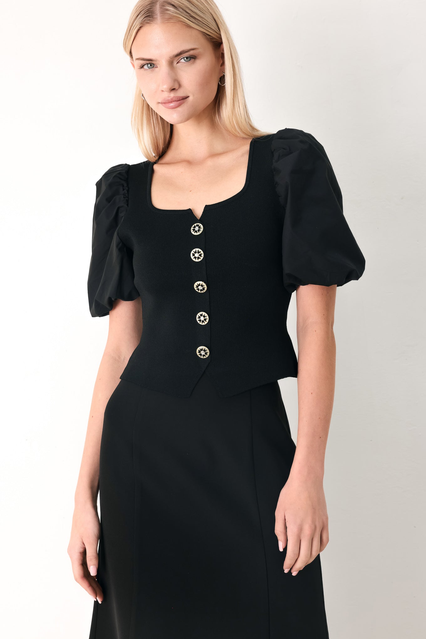 Woman wearing a black sweater knit top featuring square neckline, woven puff sleeve and front button detail | FREEMARKET