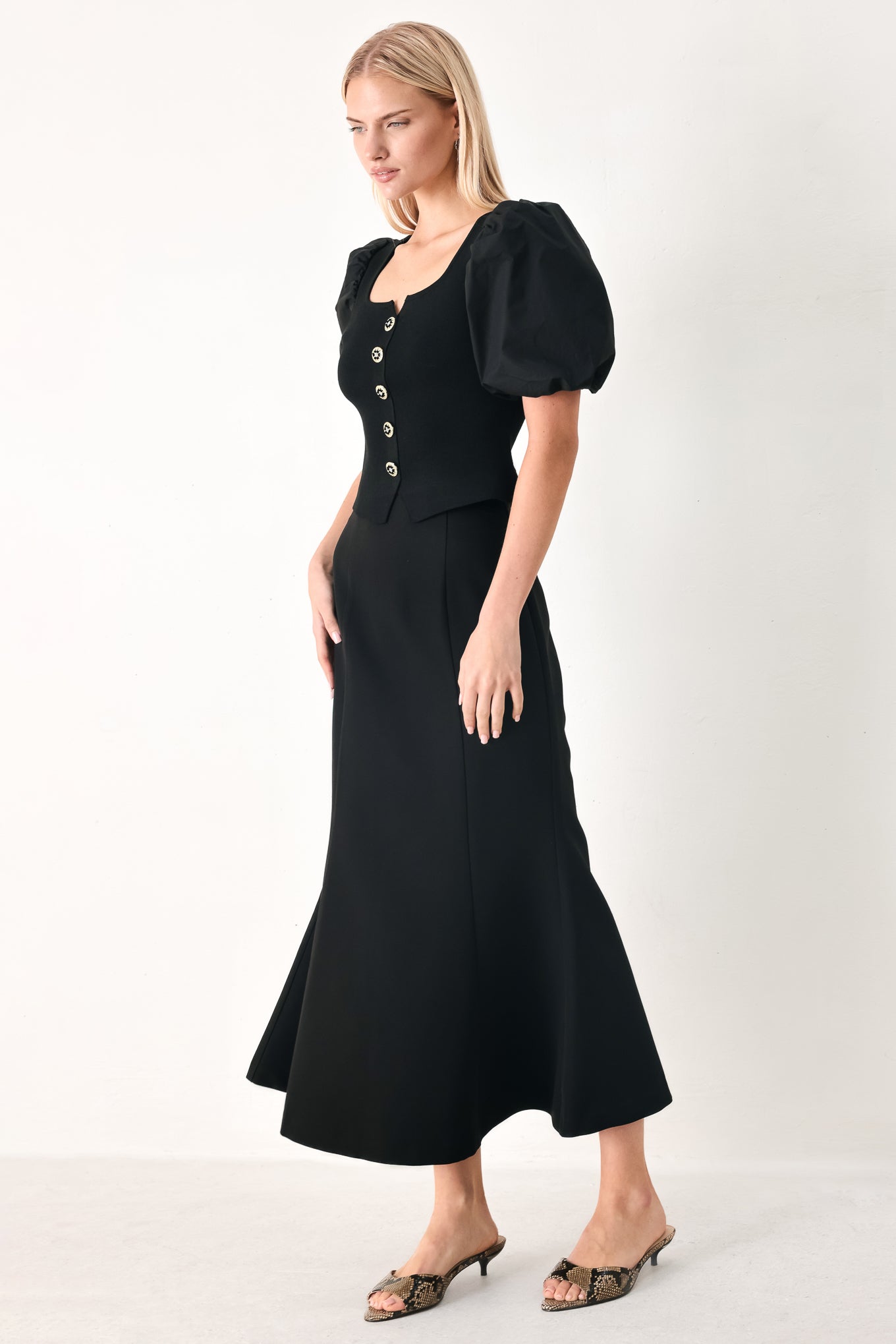 Woman wearing a black sweater knit top featuring square neckline, woven puff sleeve and front button detail | FREEMARKET