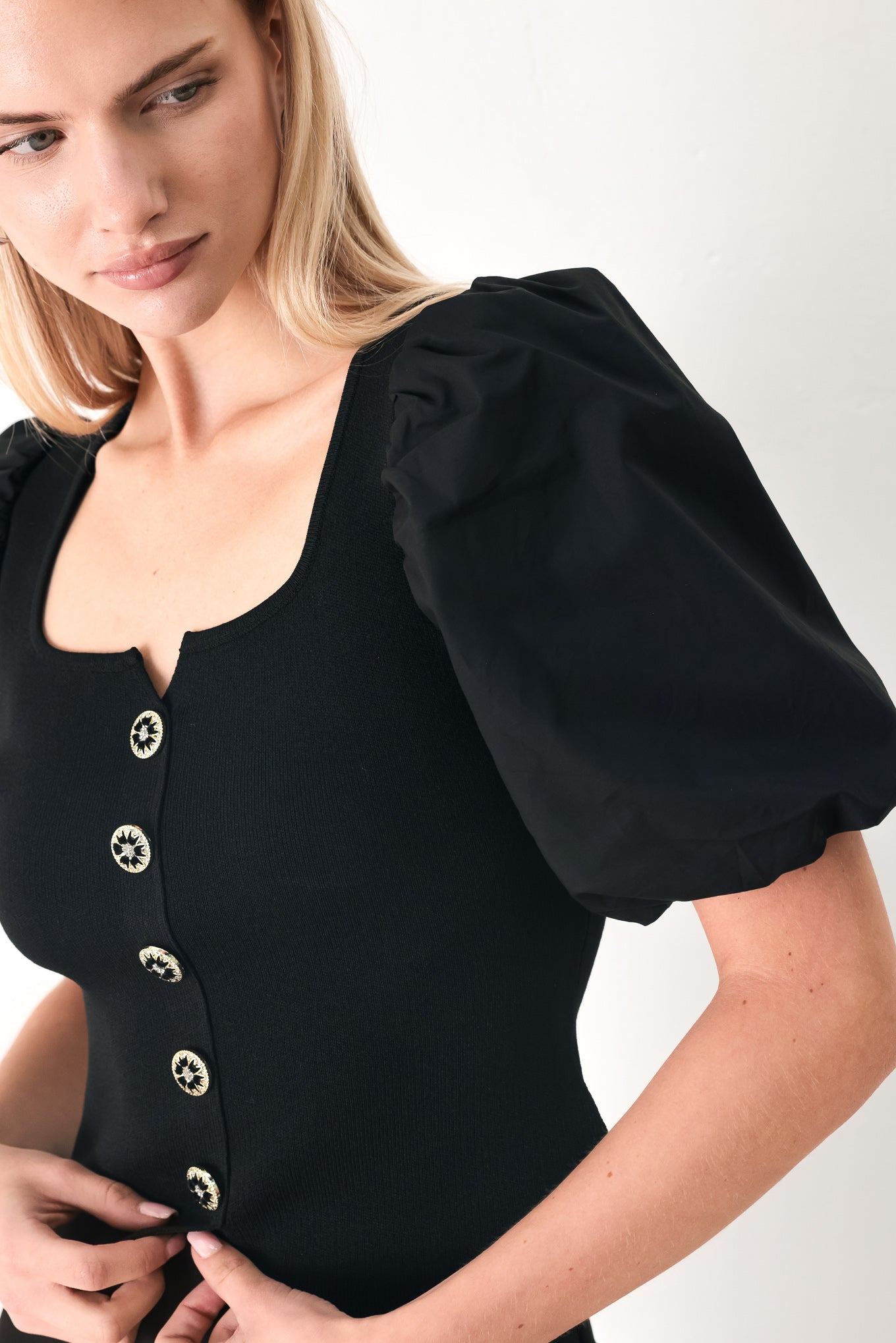 Woman wearing a black sweater knit top featuring square neckline, woven puff sleeve and front button detail | FREEMARKET