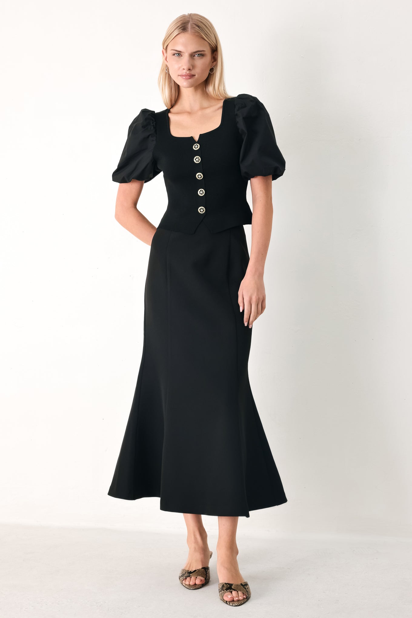 Woman wearing a black sweater knit top featuring square neckline, woven puff sleeve and front button detail | FREEMARKET